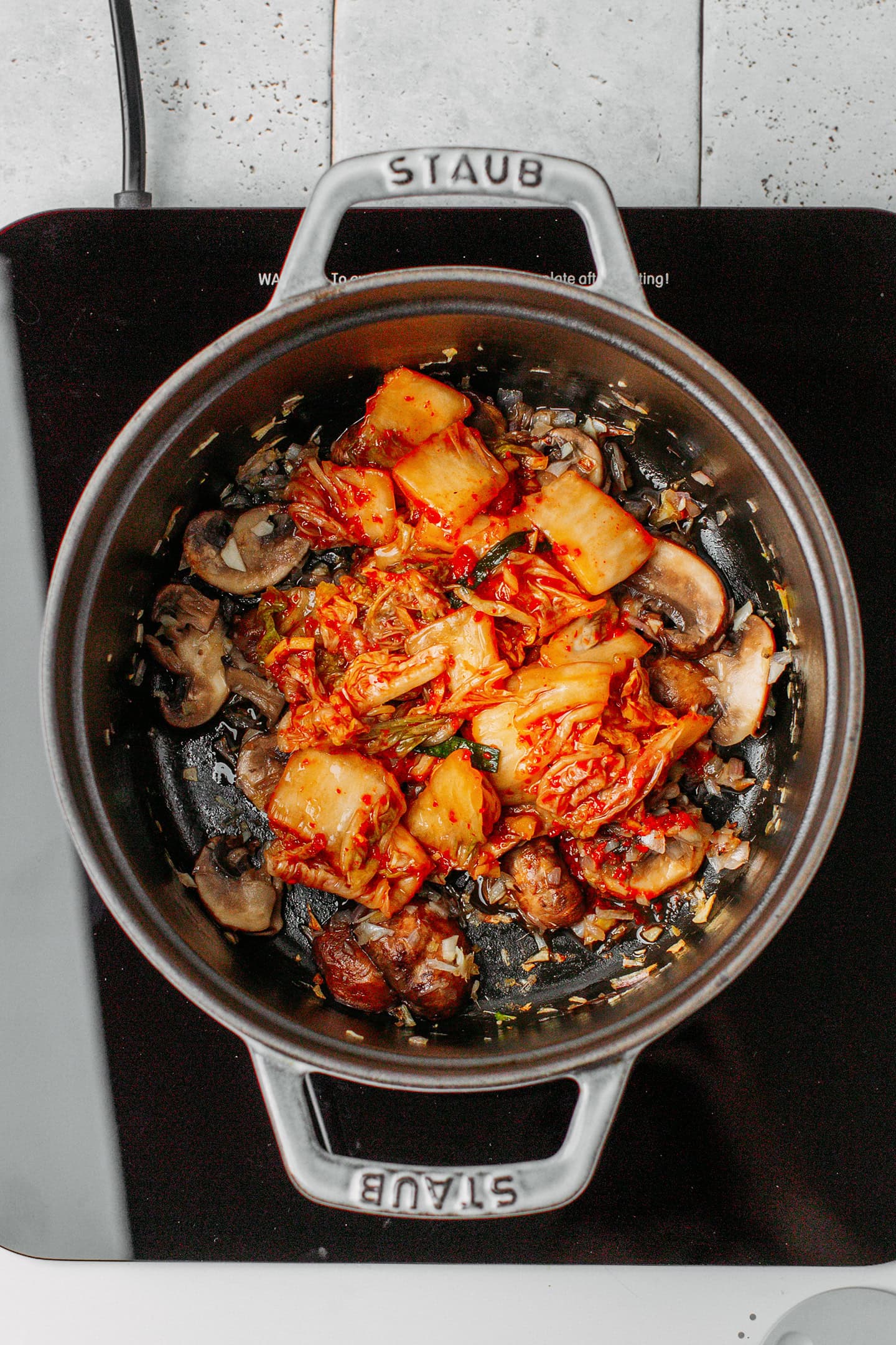 Sautéed mushrooms and kimchi in a pot.