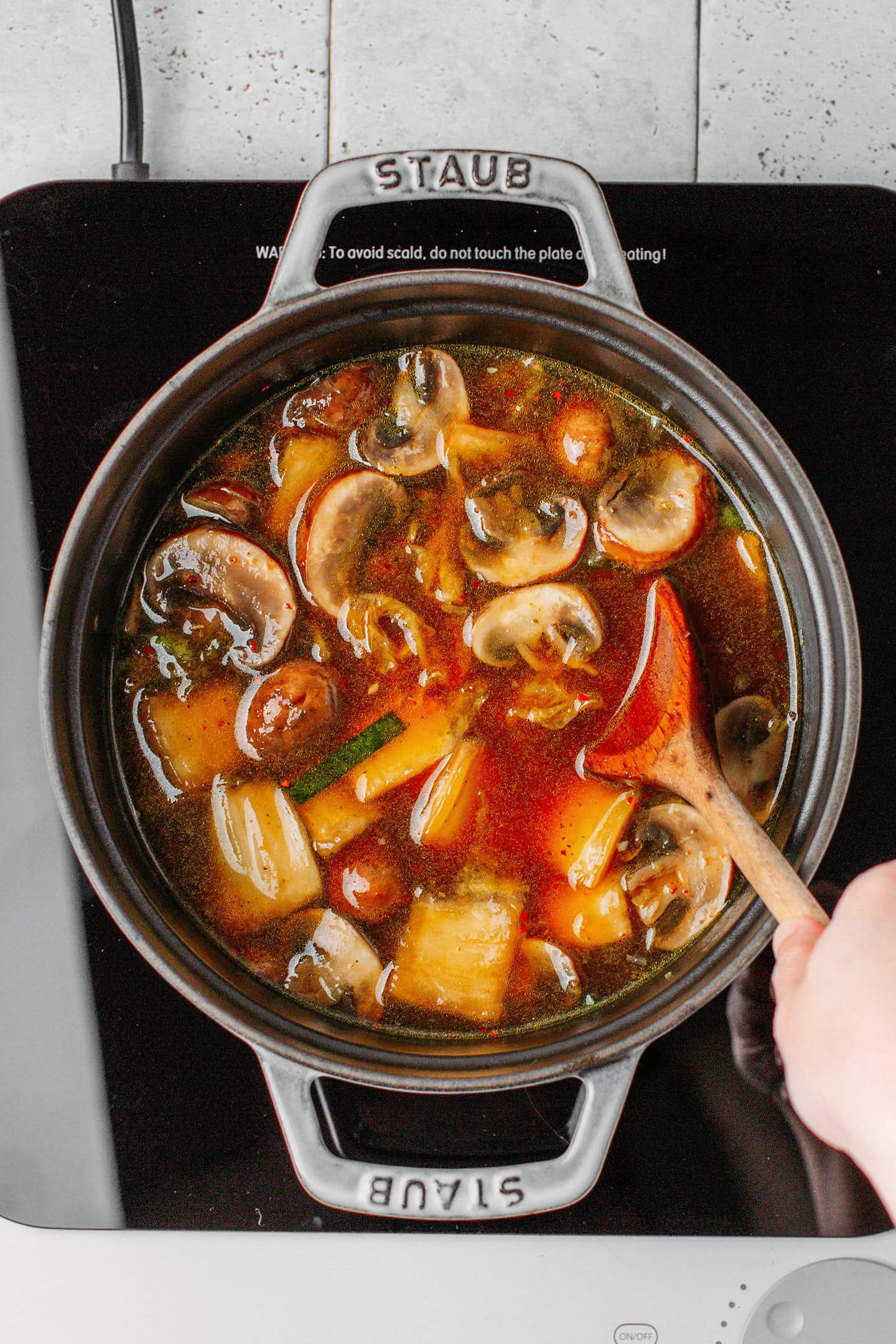 Stirring kimchi broth in a pot.