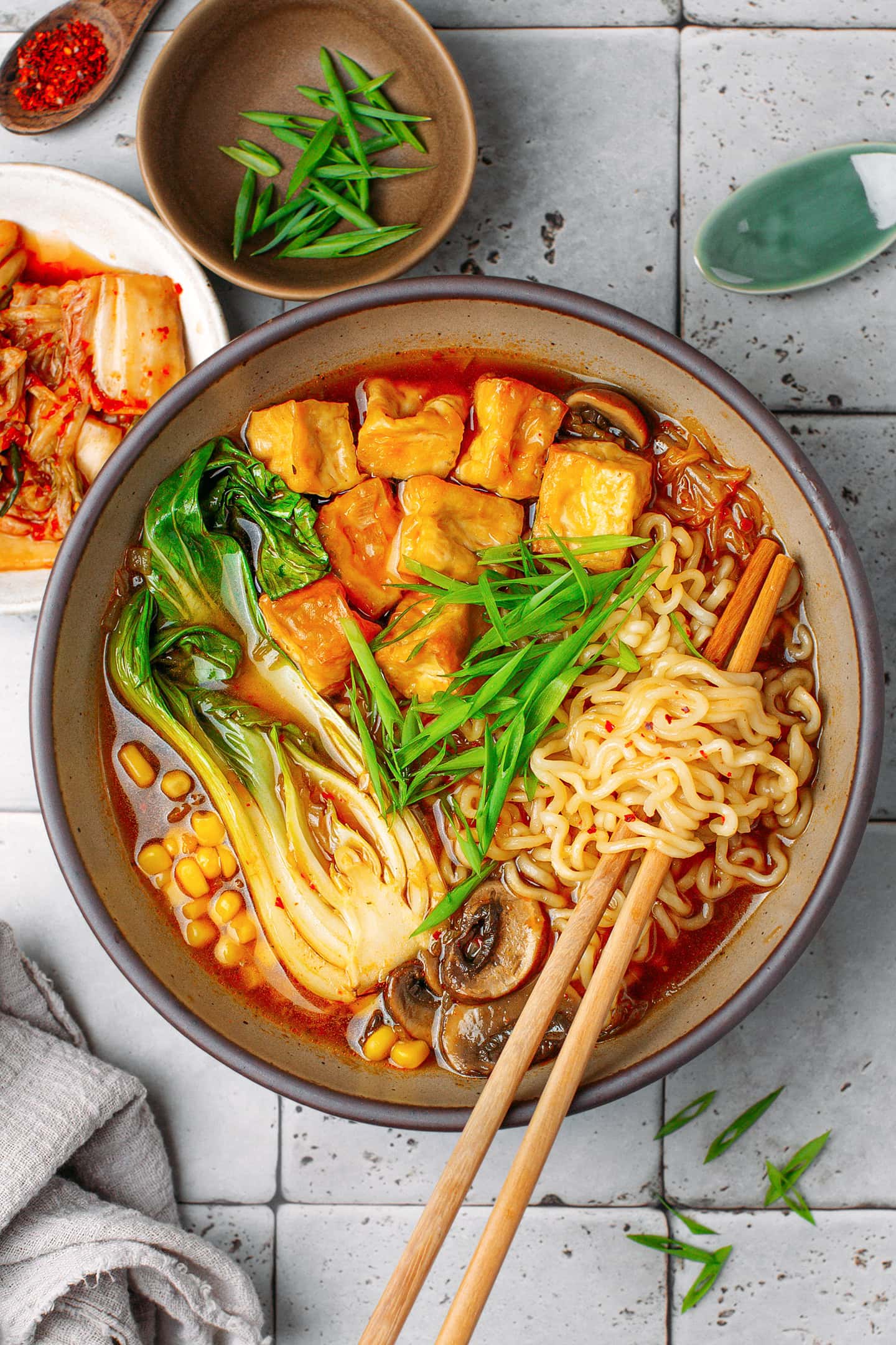 Bowl of kimchi ramen with noodles, pak choy, tofu, and mushrooms.