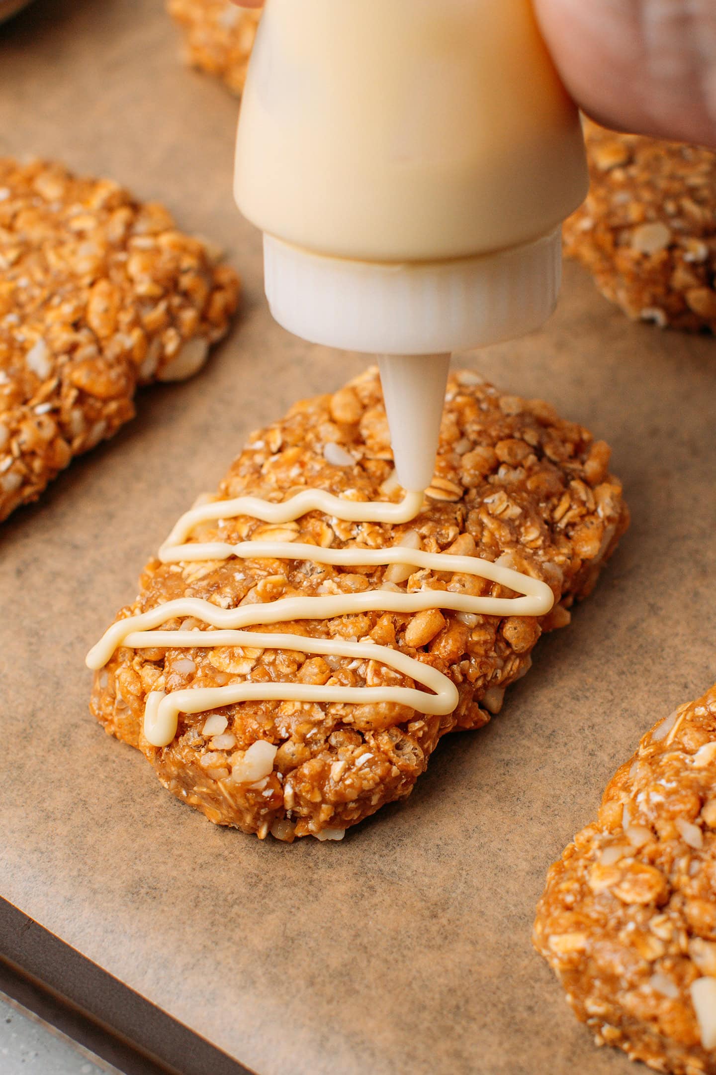 Using a squeeze bottle to drizzle a granola bar with melted white chocolate.