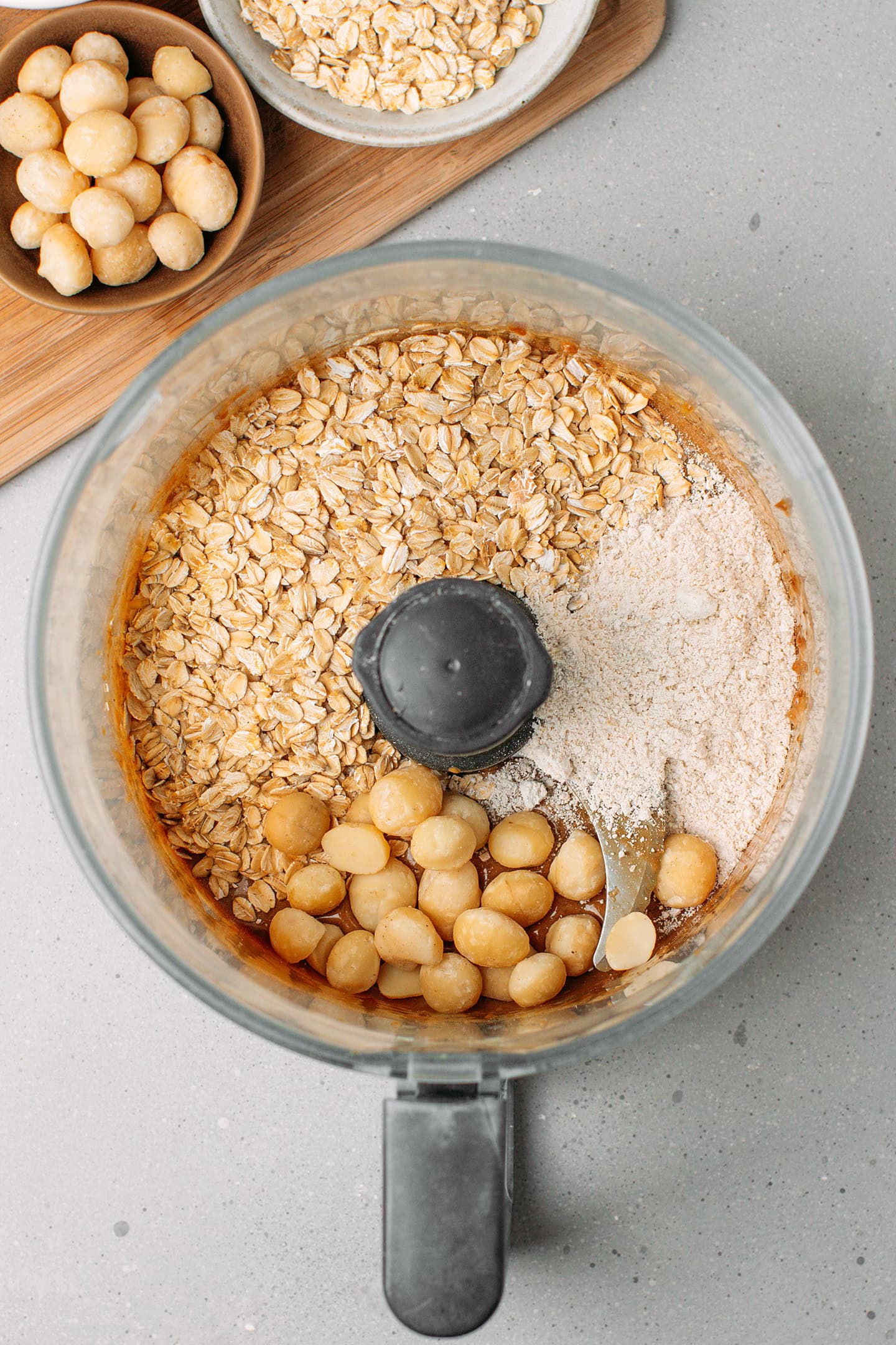 Rolled oats, macadamia nuts, and oat flour in a food processor.