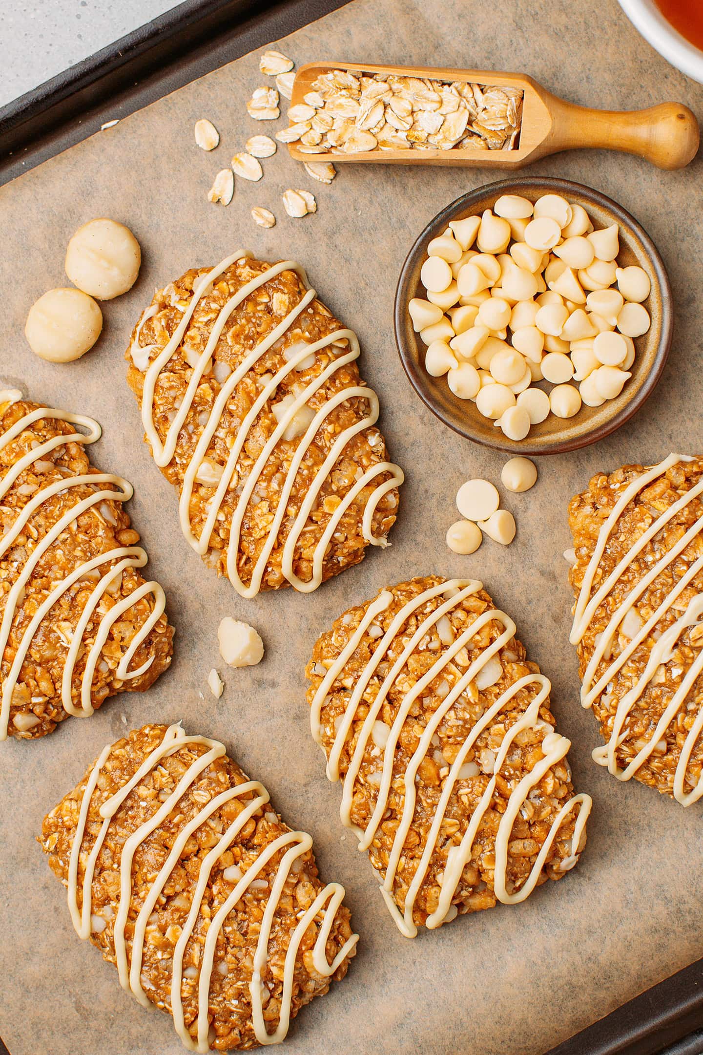 Homemade soft granola bars, with macadamia nuts and a drizzle of white chocolate, arranged on a baking sheet.