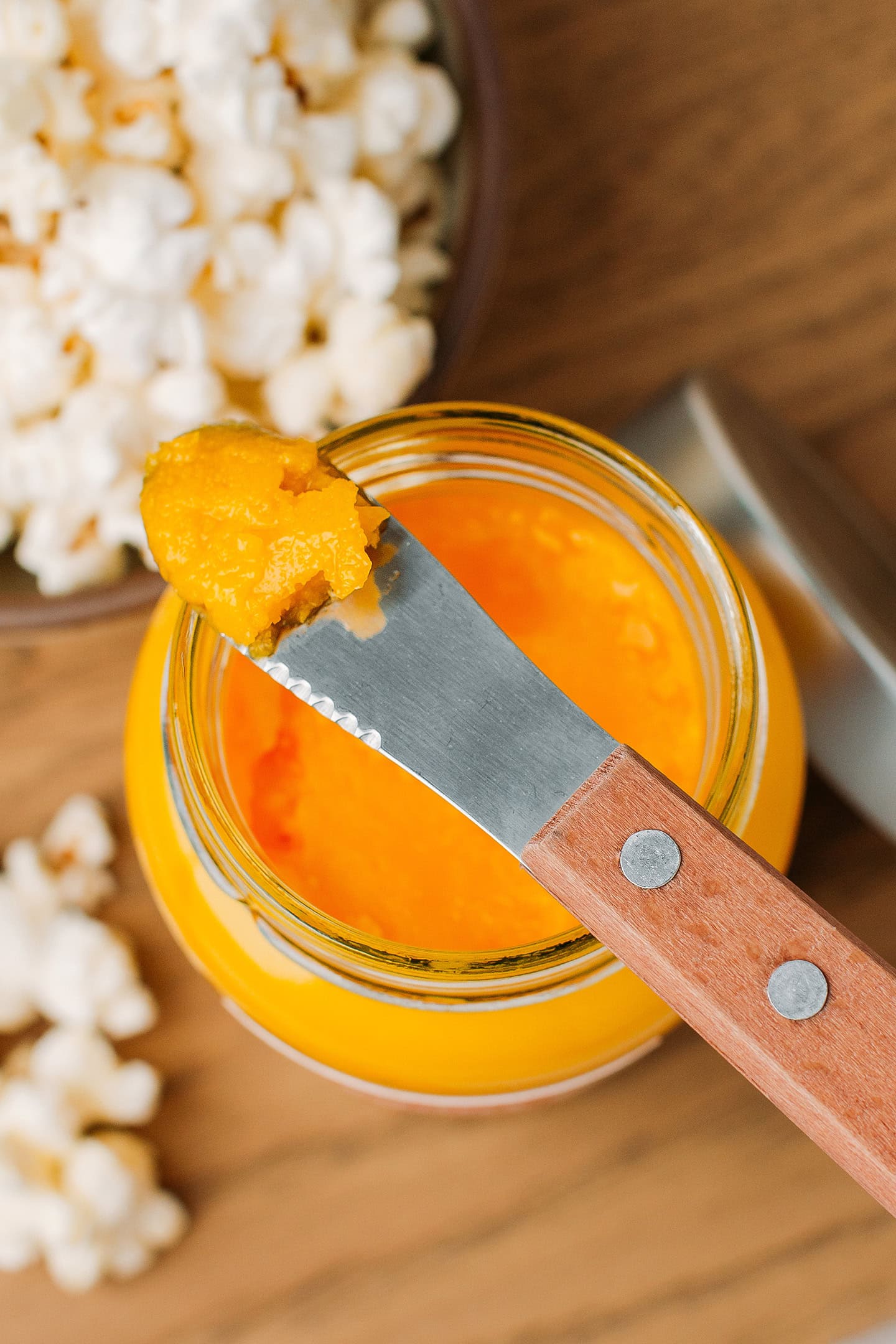 Close-up of a butter knife with thick orange coconut oil on top.