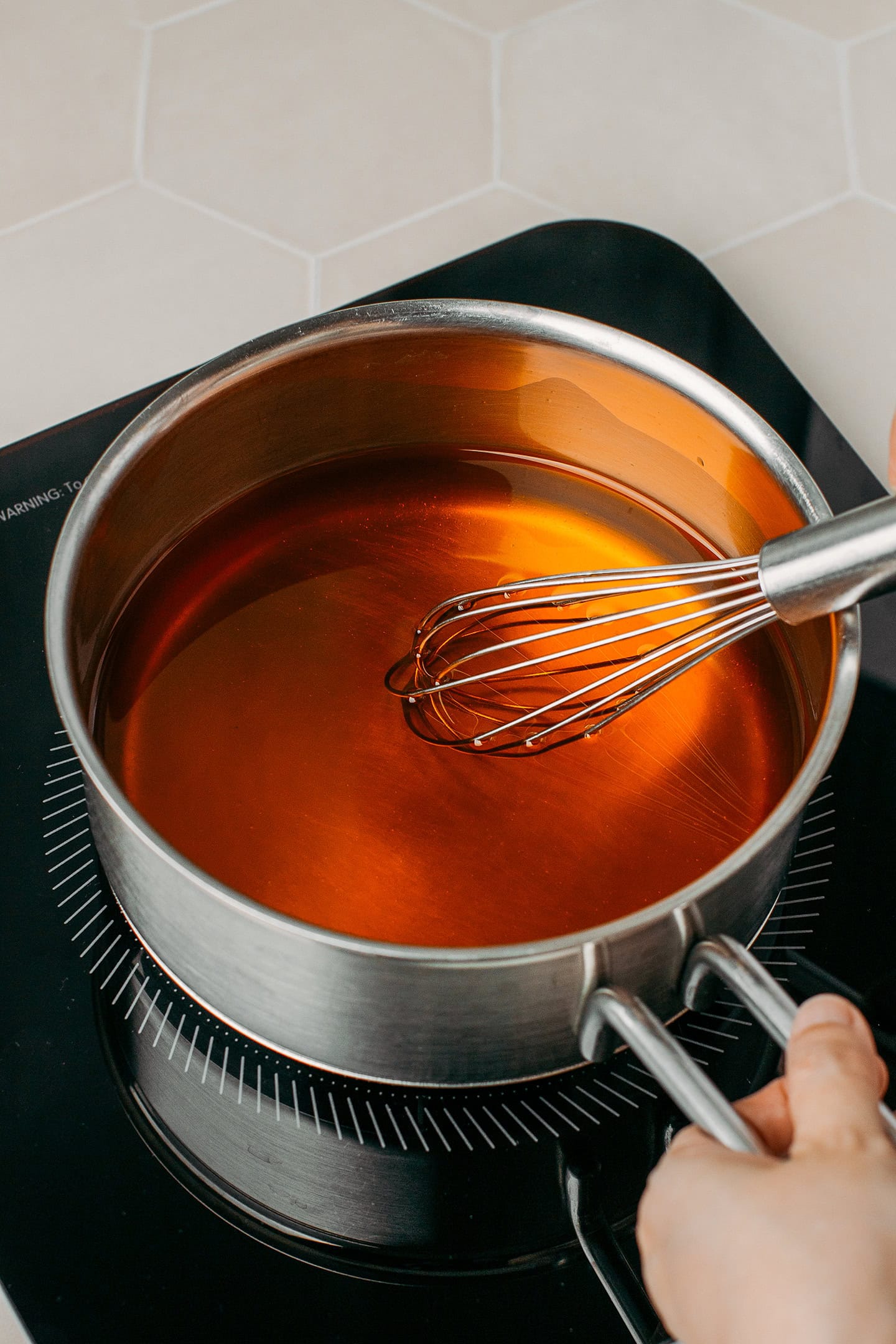 Whisking melted coconut oil and butter flavor in a saucepan.