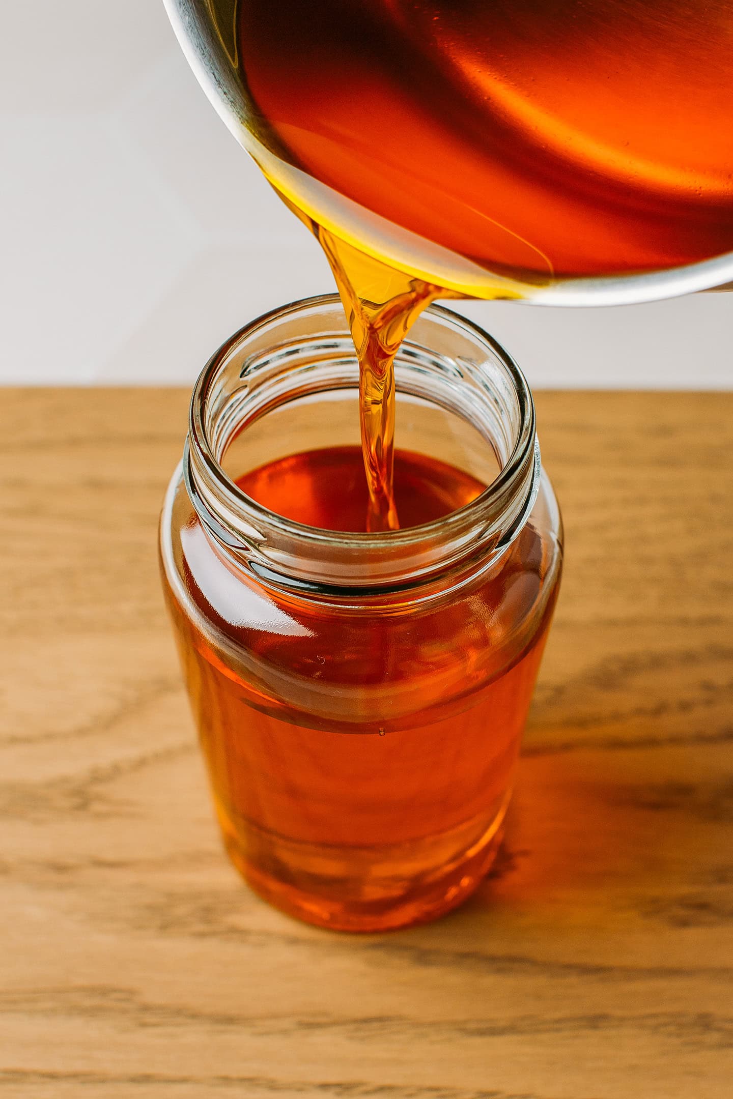 Pouring butter-flavored coconut oil into a glass jar.