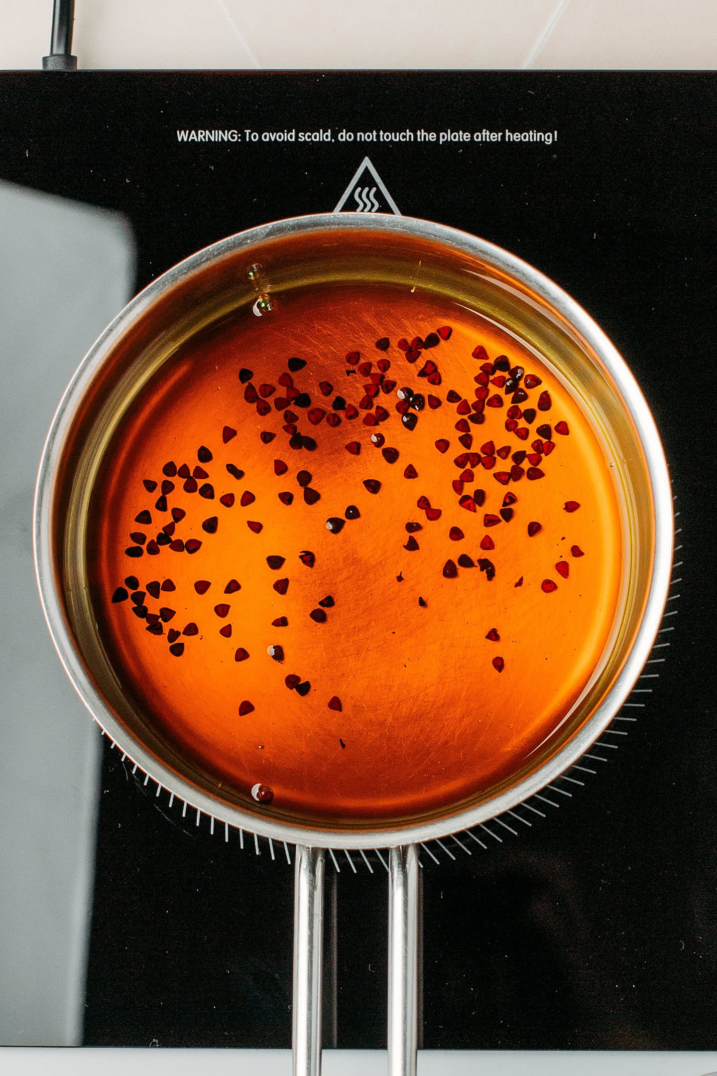 Coconut oil colored with annatto seeds in a saucepan.