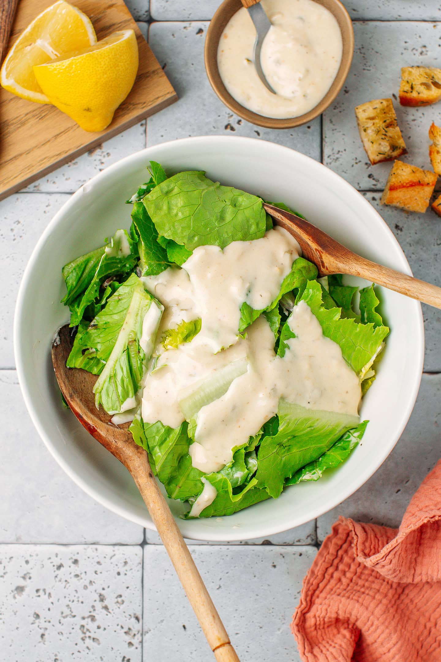 Chopped Romaine salad and dressing in a mixing bowl.