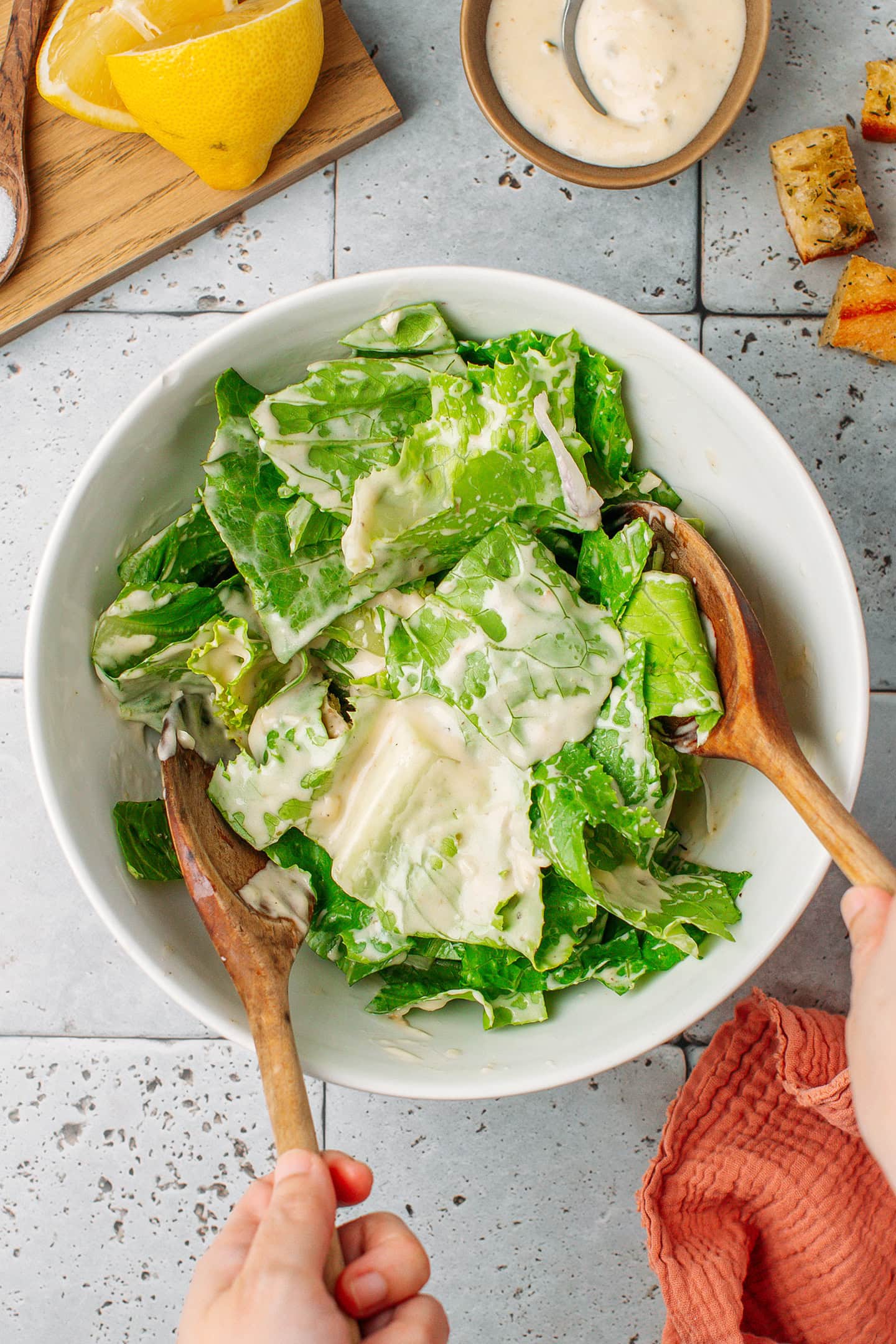 Tossing salad with a creamy dressing in a mixing bowl.