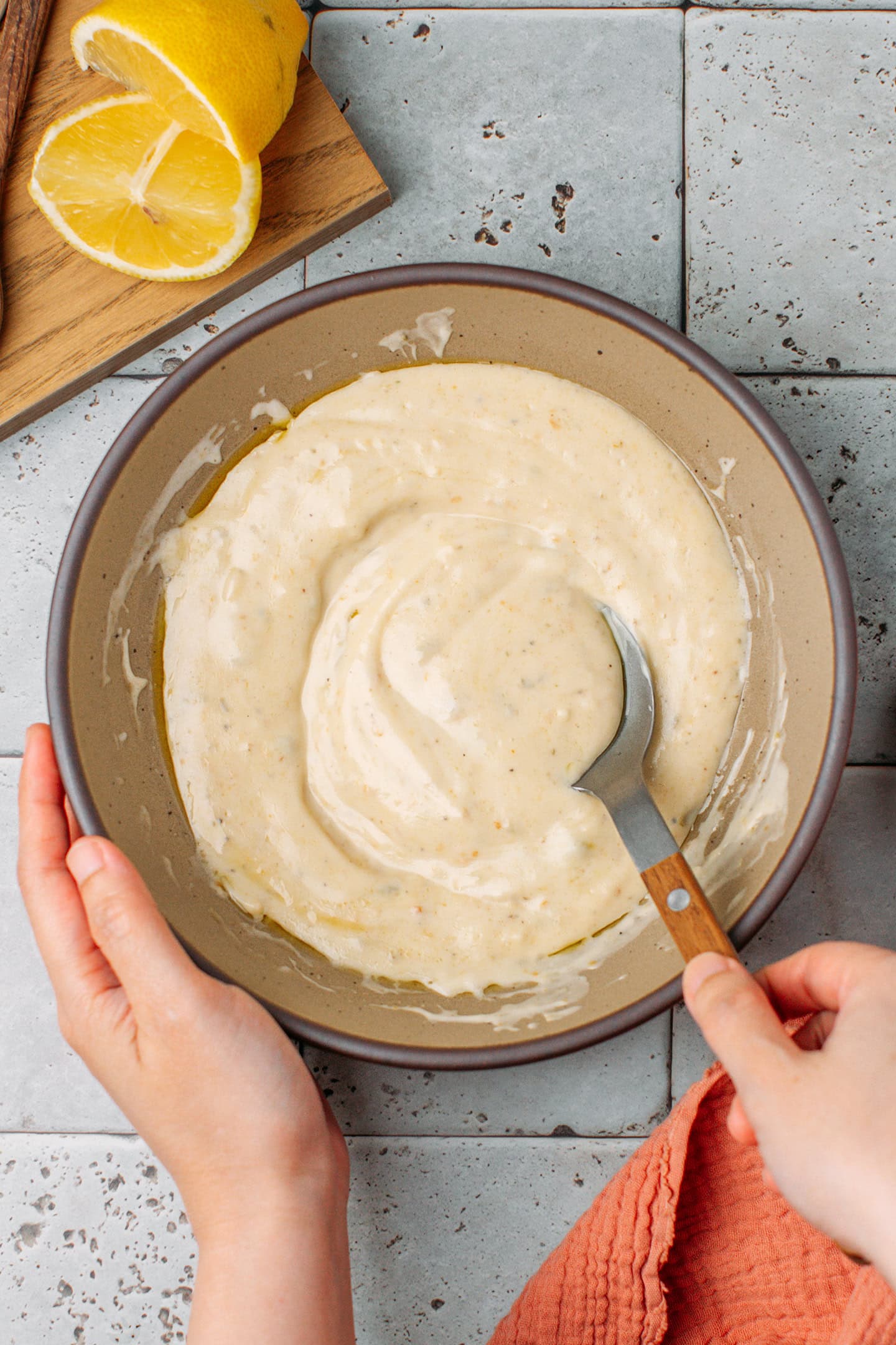 Mixing a Caesar salad dressing in a brown bowl.