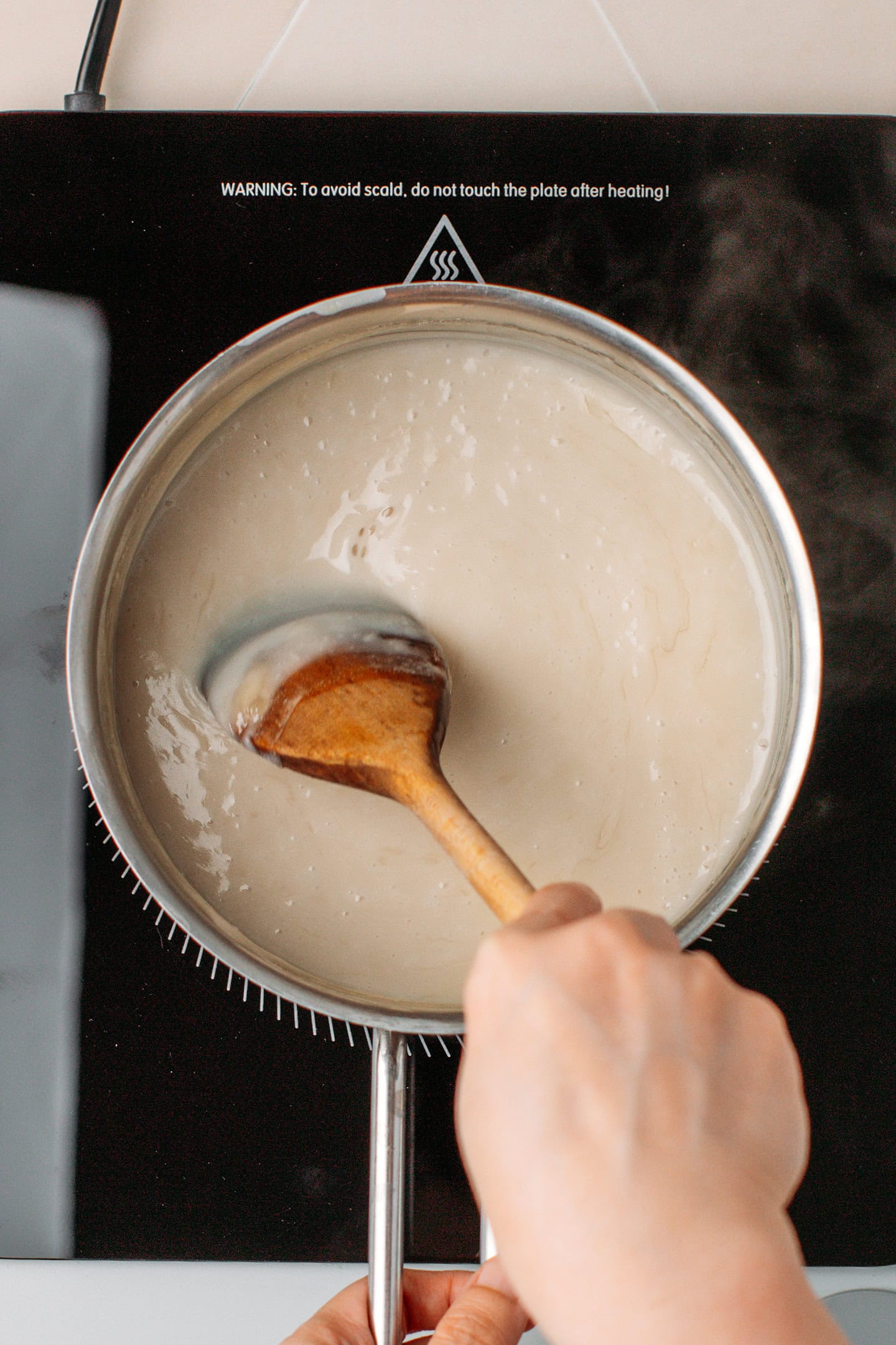 Stirring vegan condensed milk in a saucepan.