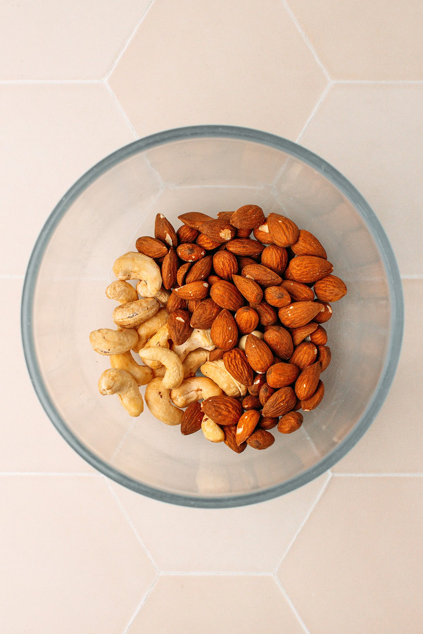 Raw almonds and cashews in a glass bowl.