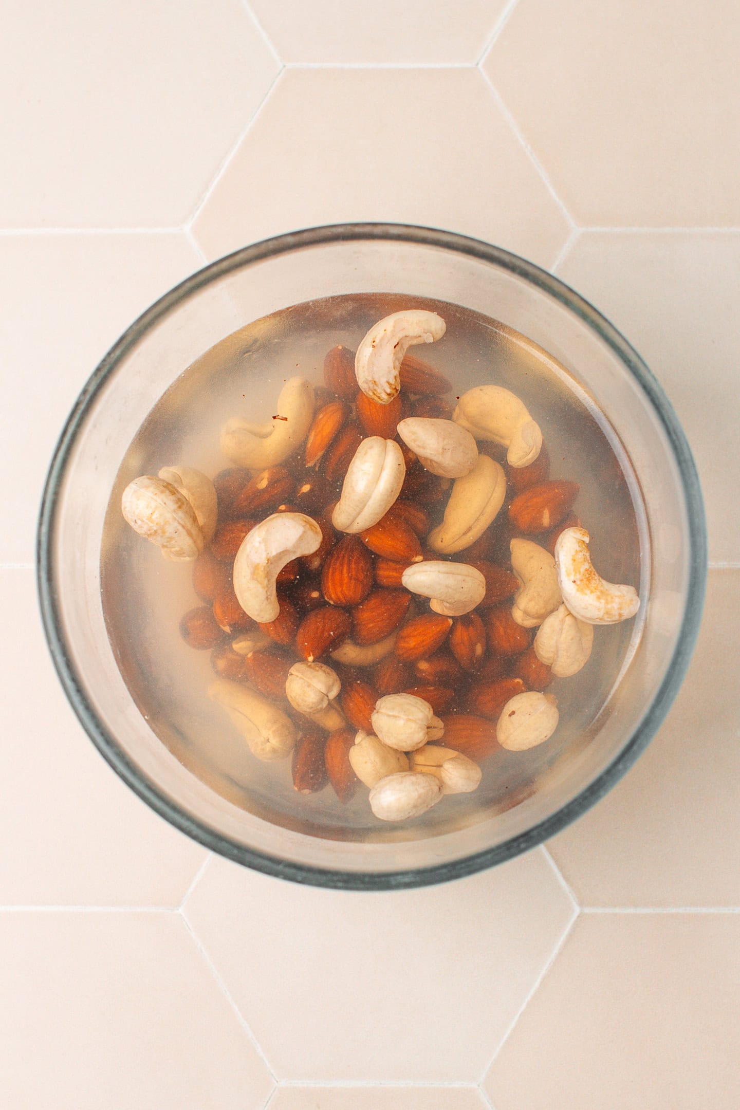 Almonds and cashews soaking in a bowl of water.