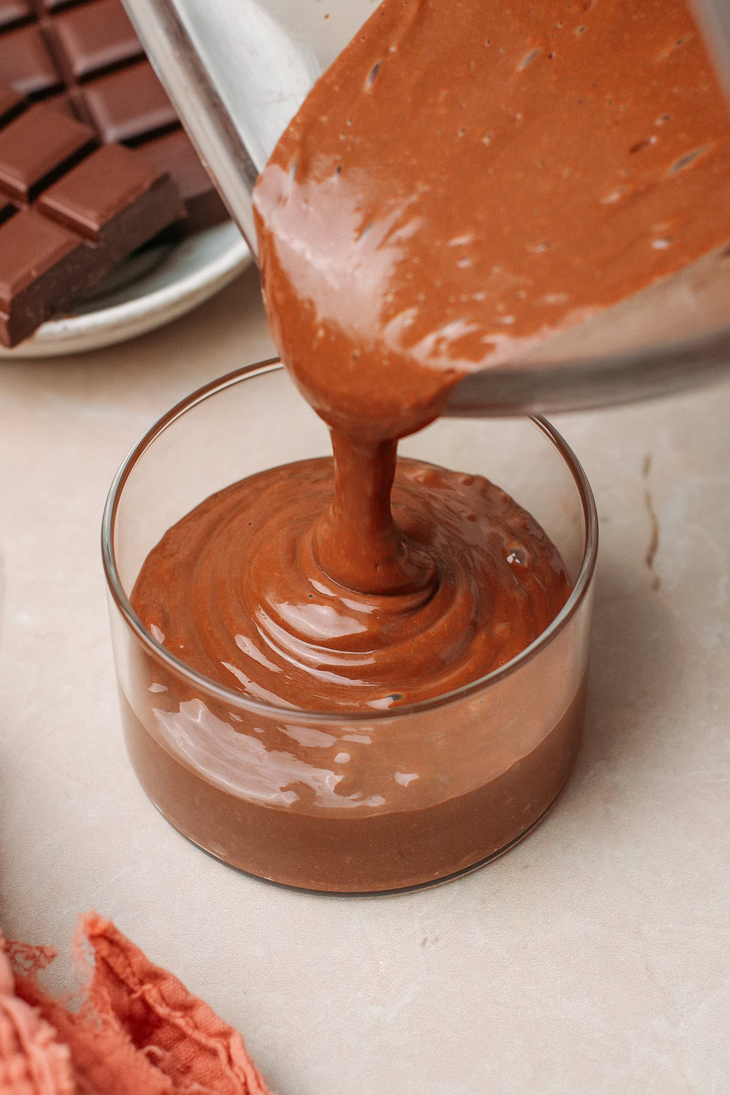 Pouring chocolate mousse into a glass ramekin.
