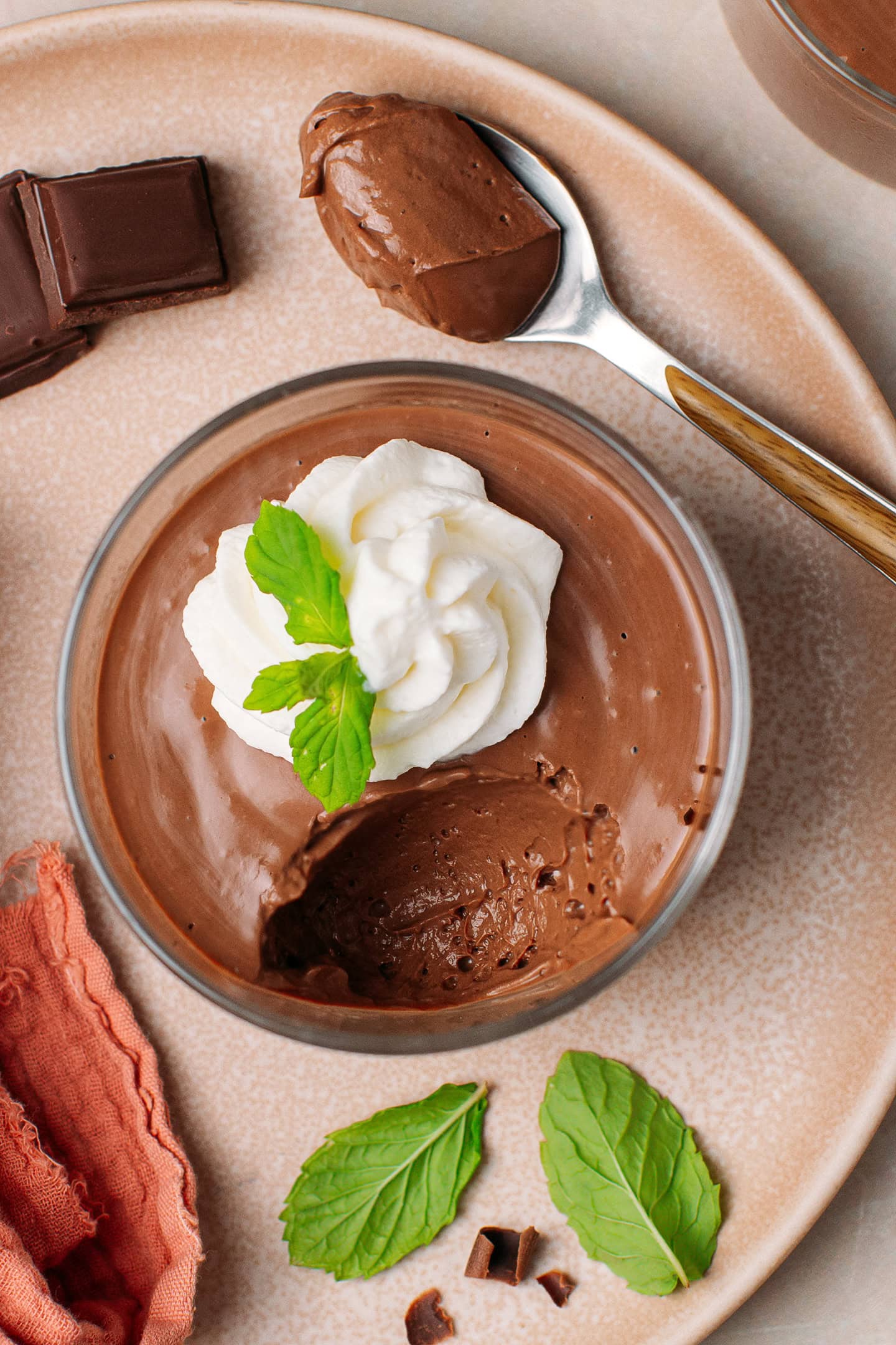 Top view of a chocolate mousse garnished with whipping cream and mint leaves.