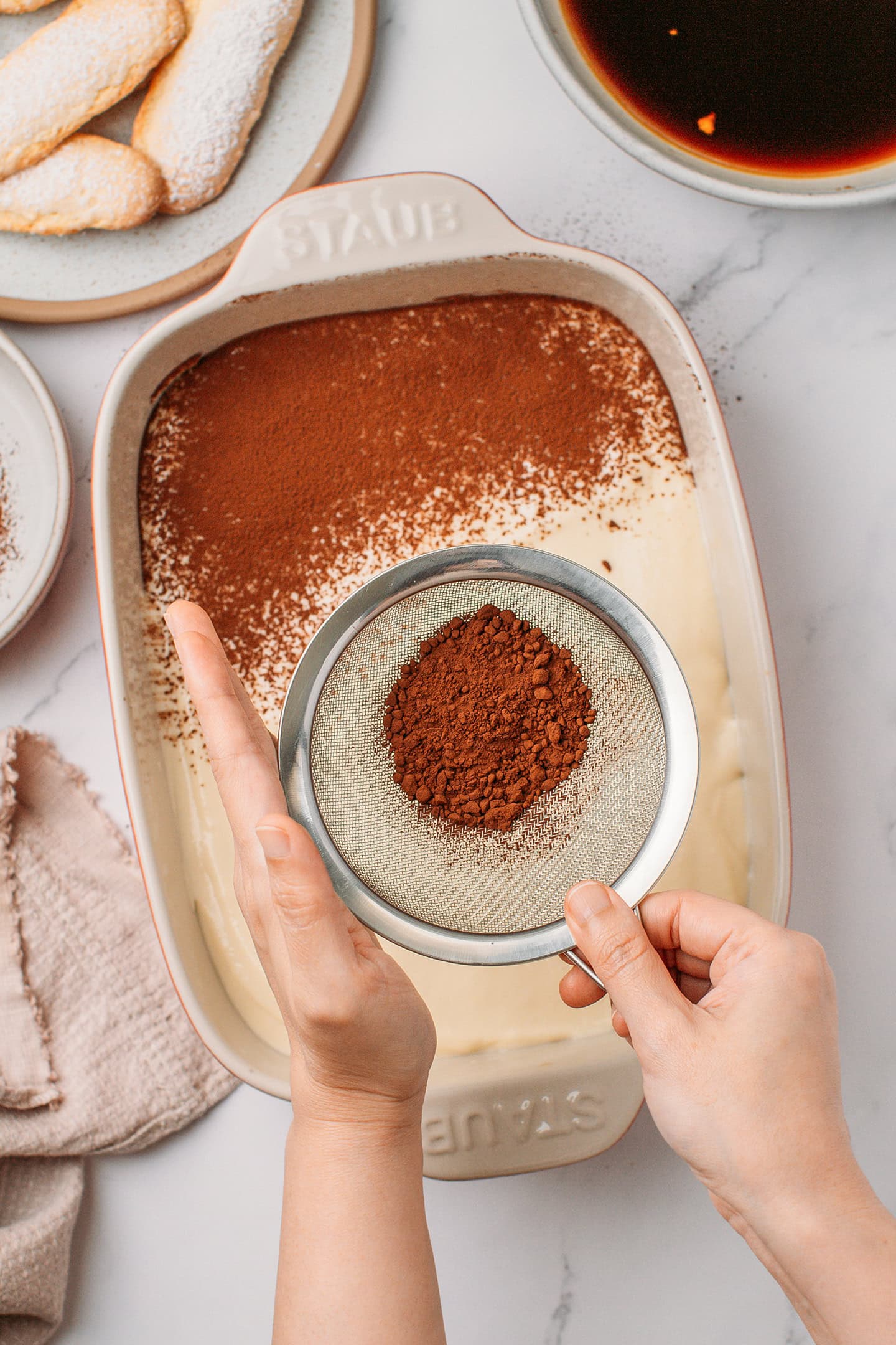Dusting cocoa powder over vanilla cream.