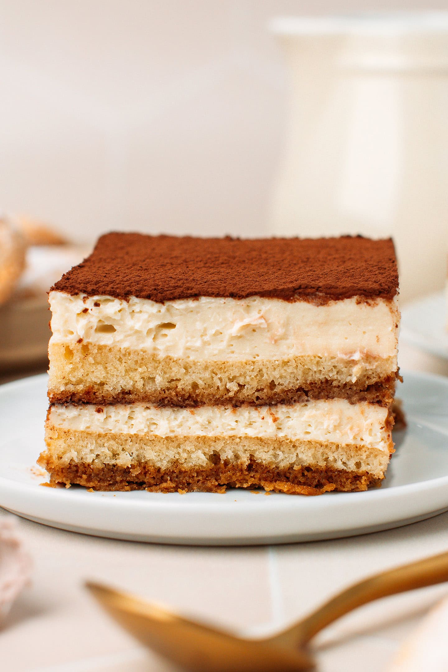 Slice of tiramisu with layers of cream, sponge cake, and cocoa powder.