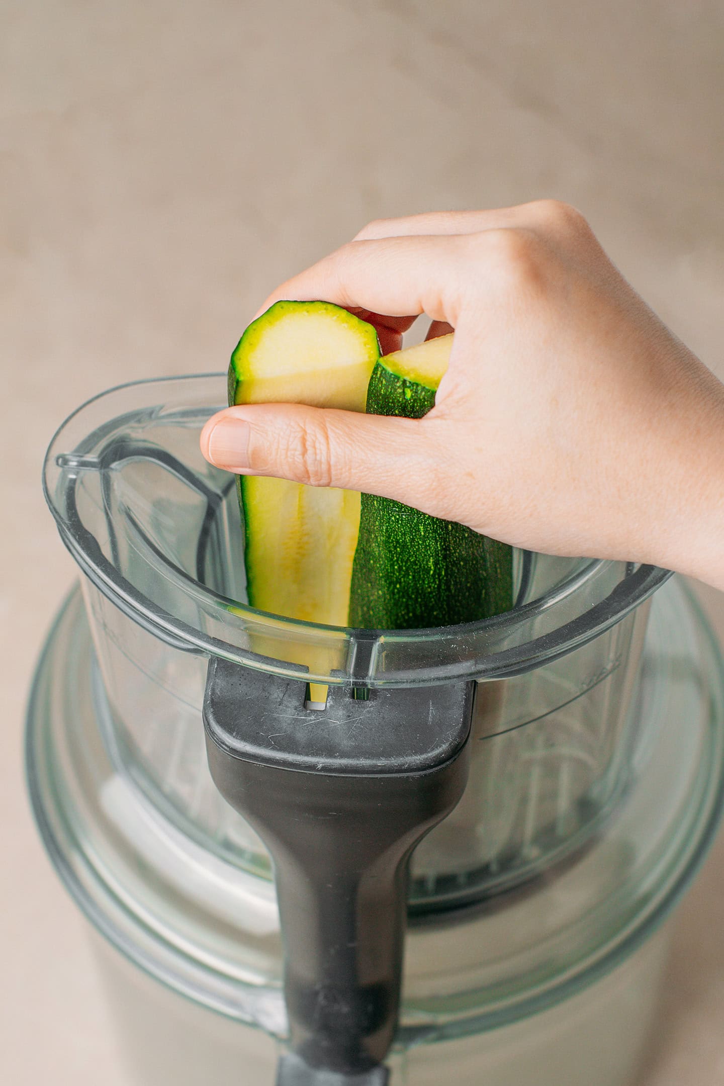 Adding zucchini to a food processor fitted with the grater disc.