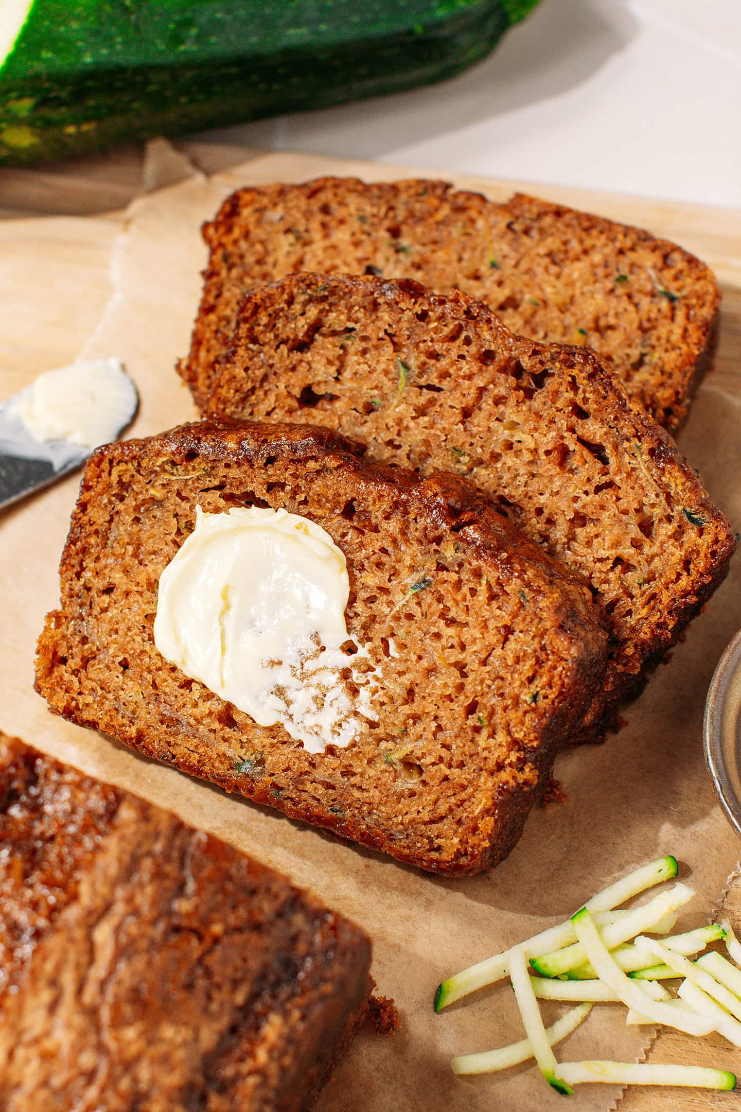 Three slices of vegan zucchini bread with a dollop of butter.