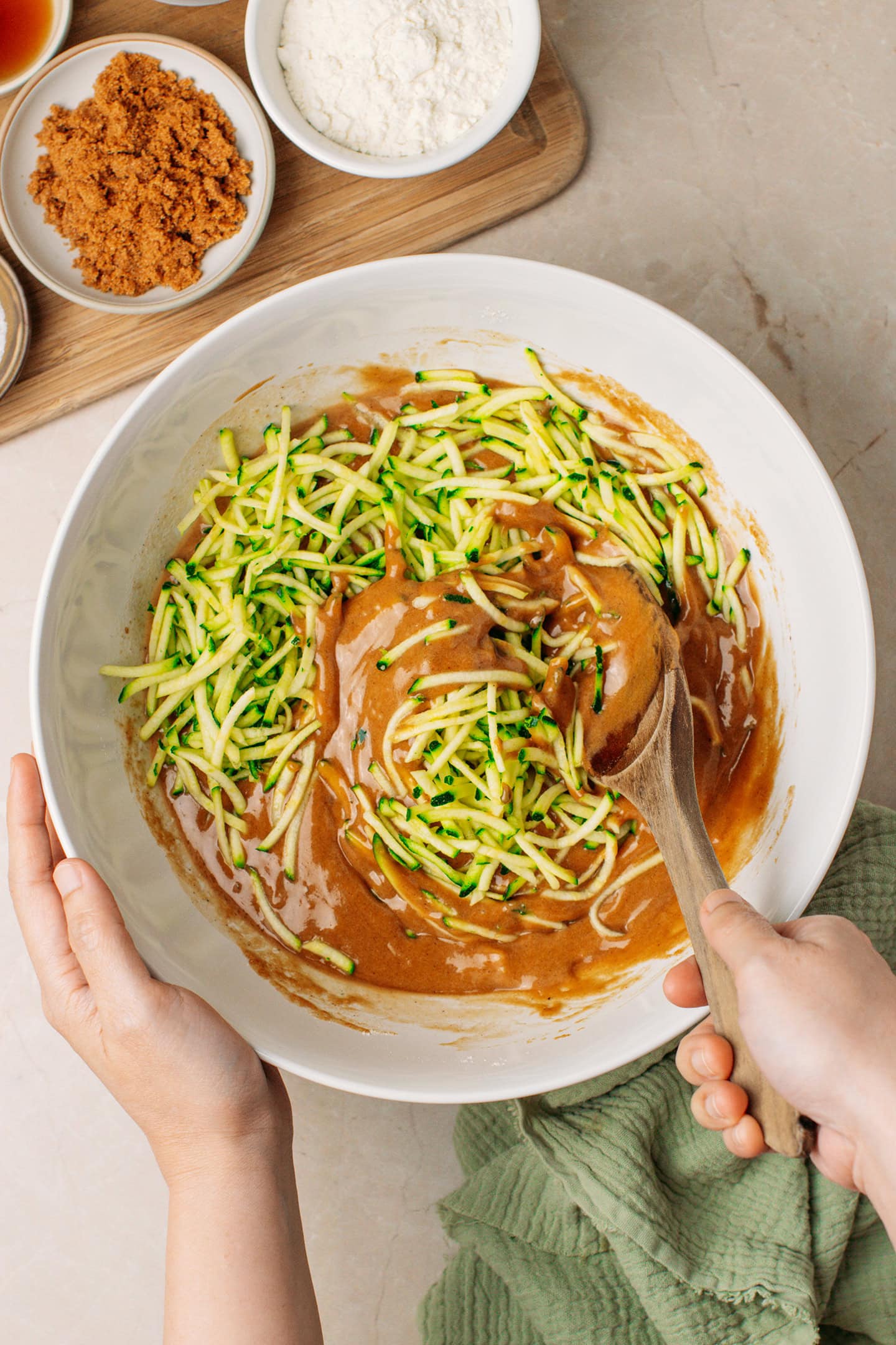 Incorporating grated zucchini into a cake batter.