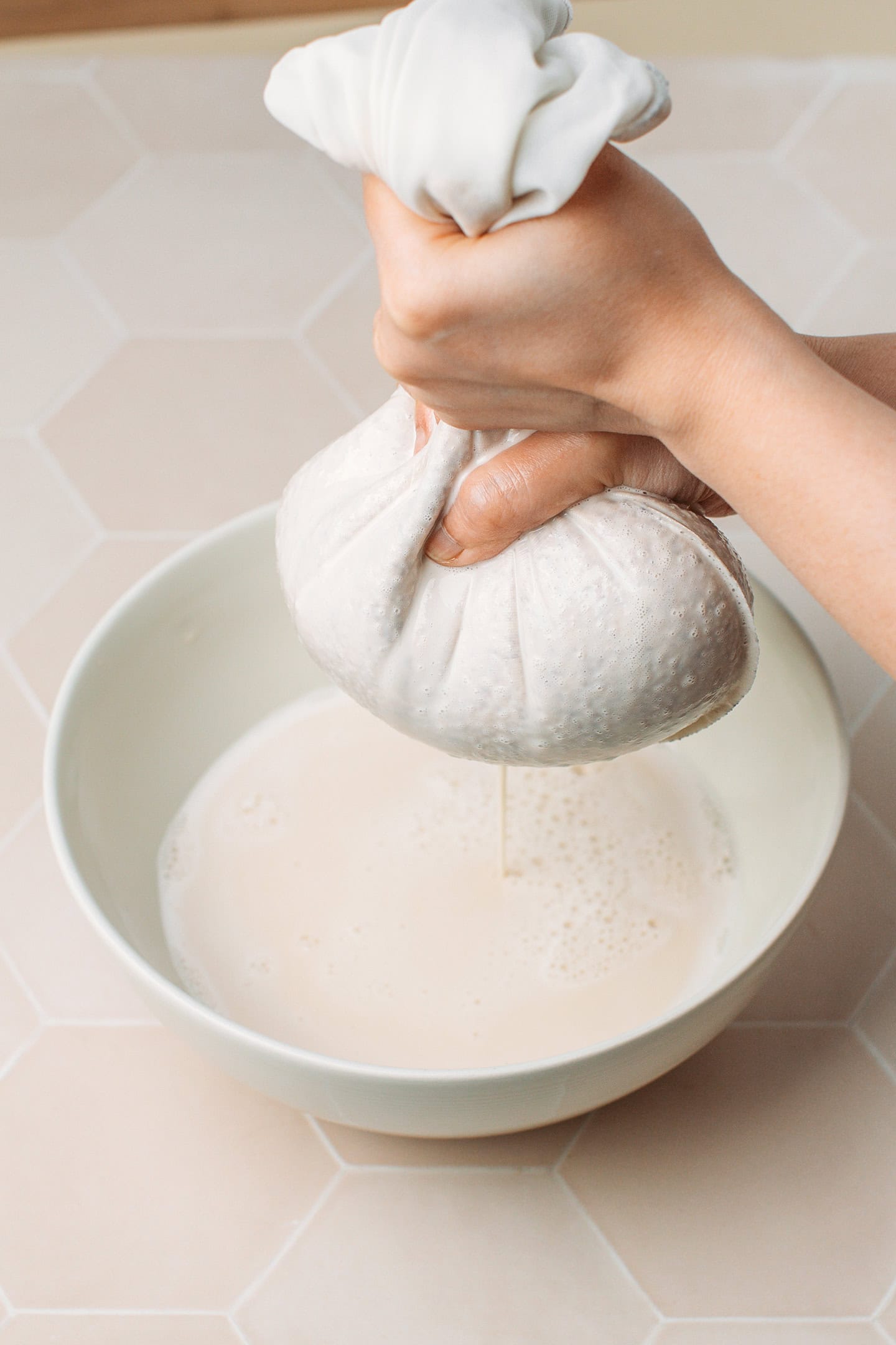 Using a nut milk bag to strain almond milk.