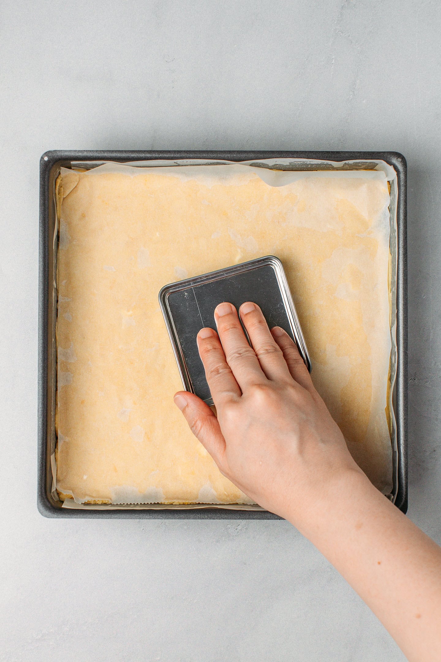 Pressing shortbread dough into a square baking pan.