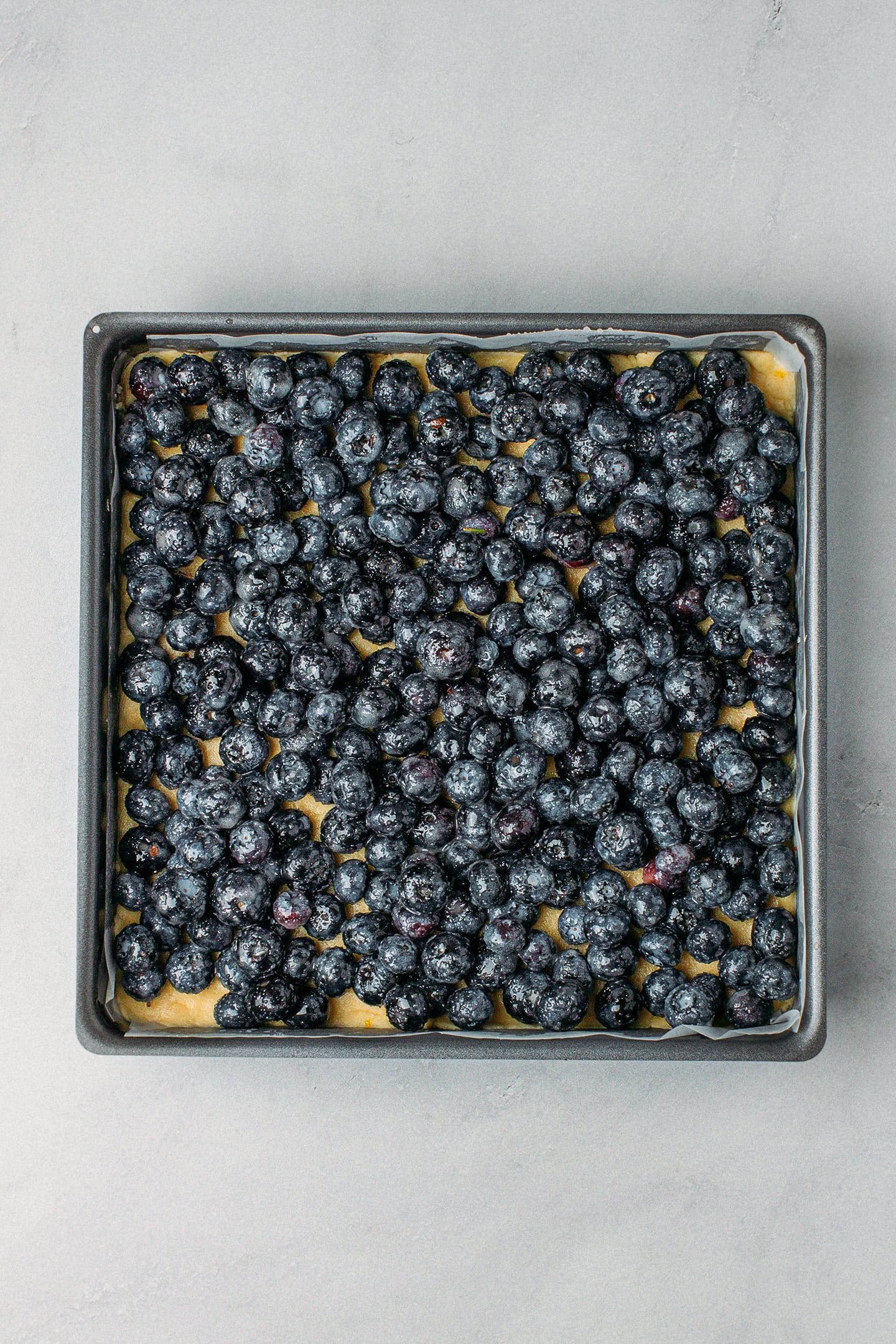 Blueberries on top of a shortbread dough in a baking pan.