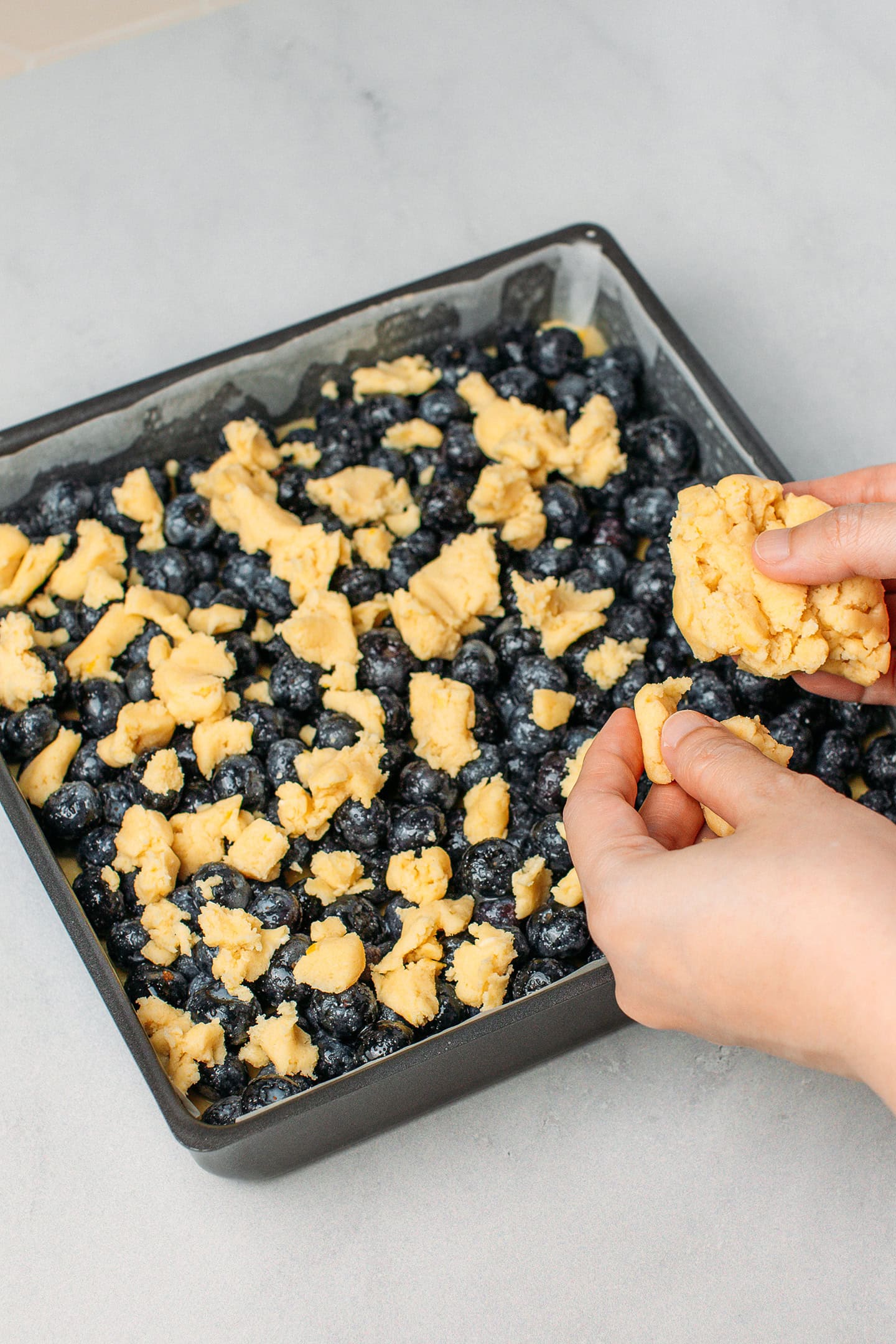 Crumbling shortbread dough over blueberries.