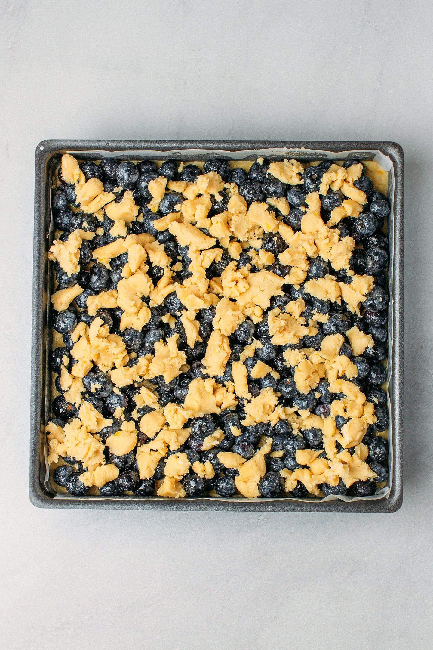 Unbaked blueberry crumble in a baking pan.