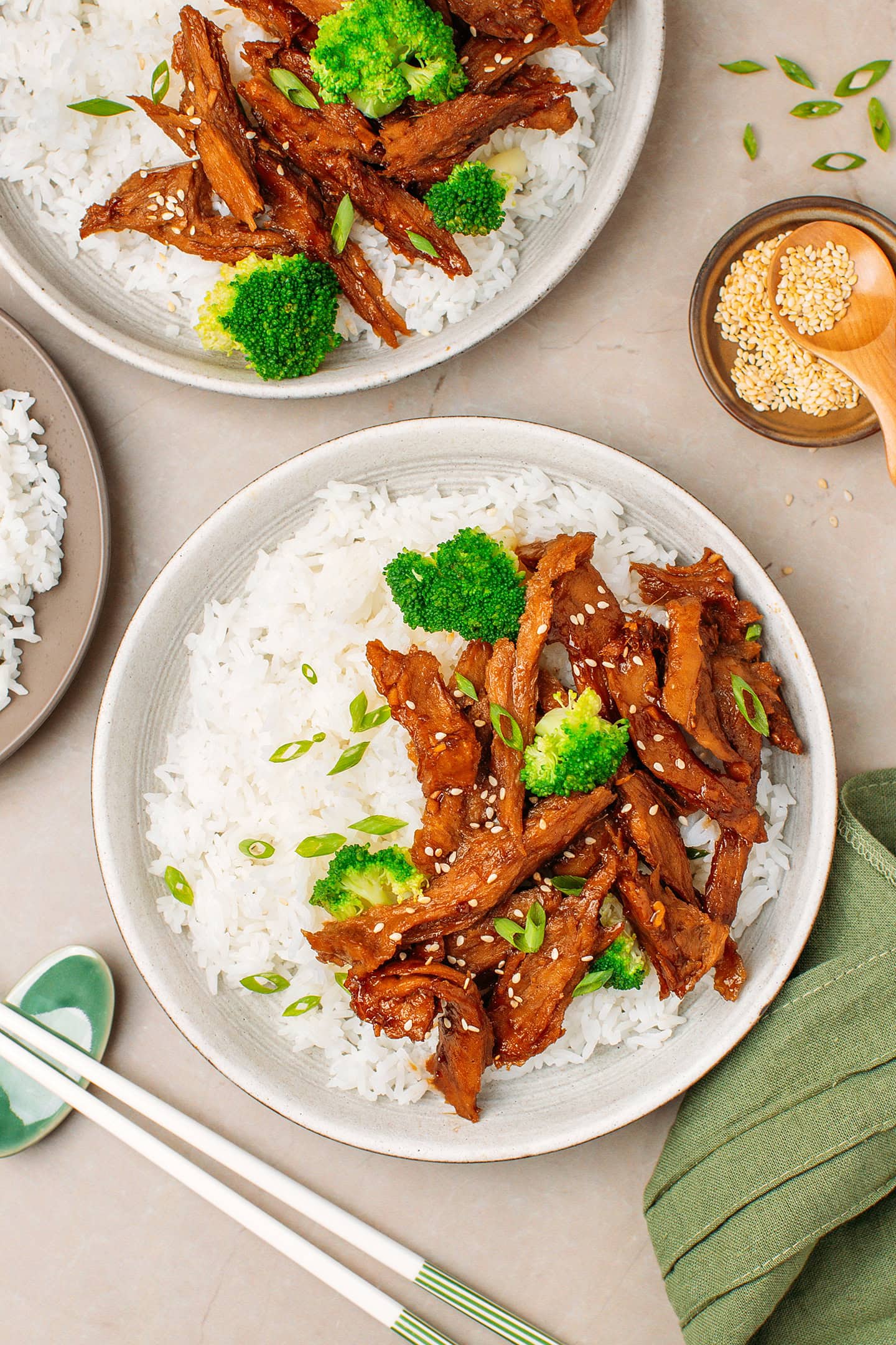 Plate filled with rice, broccoli, and vegan teriyaki chicken sprinkled with toasted sesame seeds.