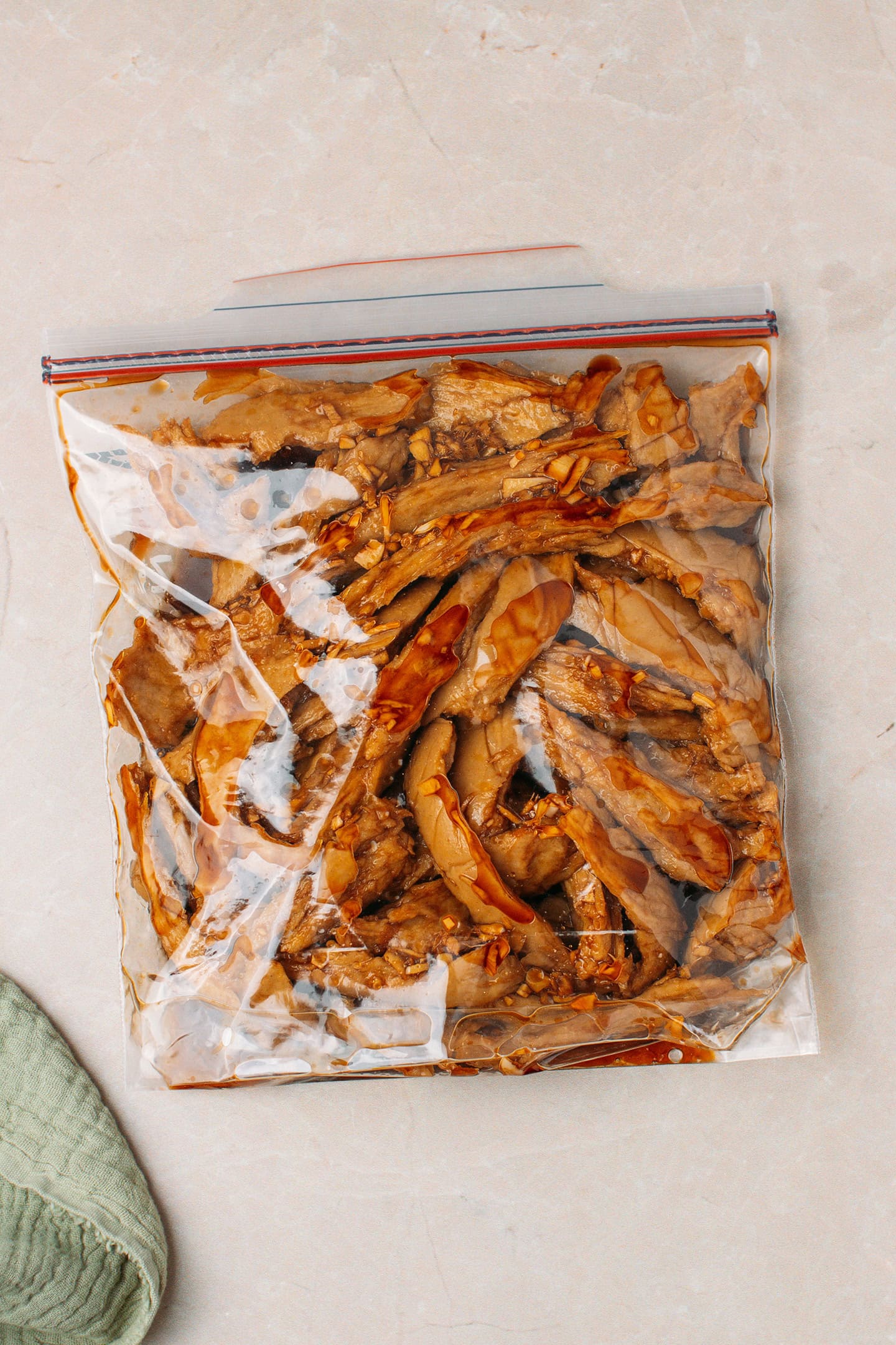Vegan chicken strips marinating in teriyaki sauce in a freezer bag.