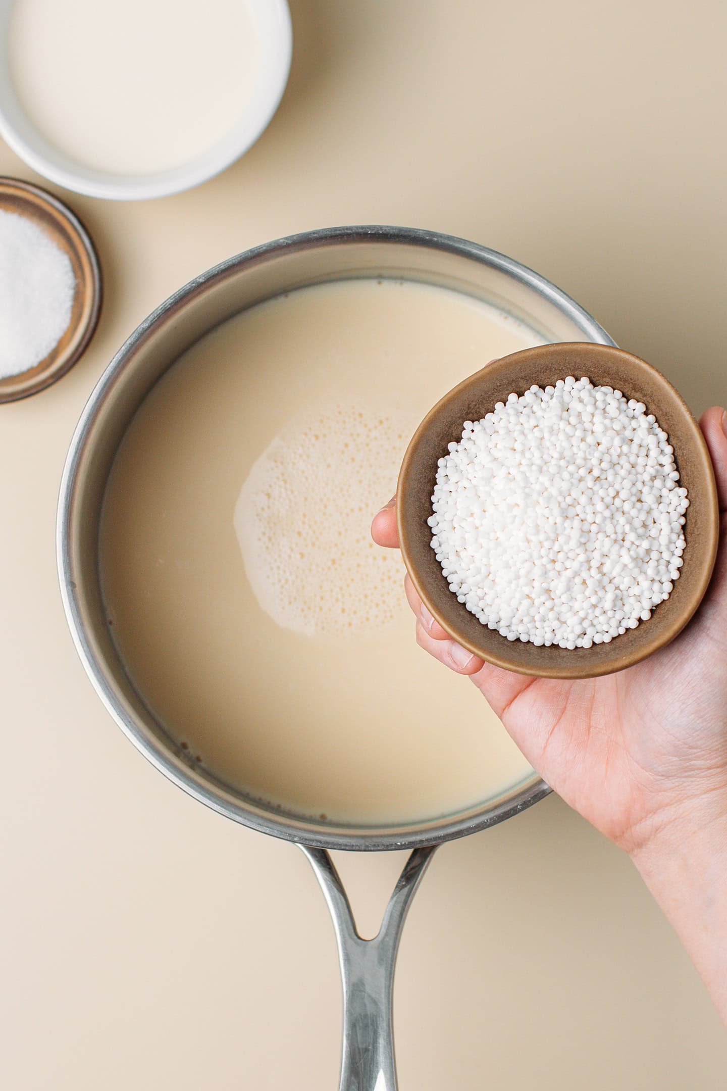 Pouring tapioca pearls into a pot containing milk.