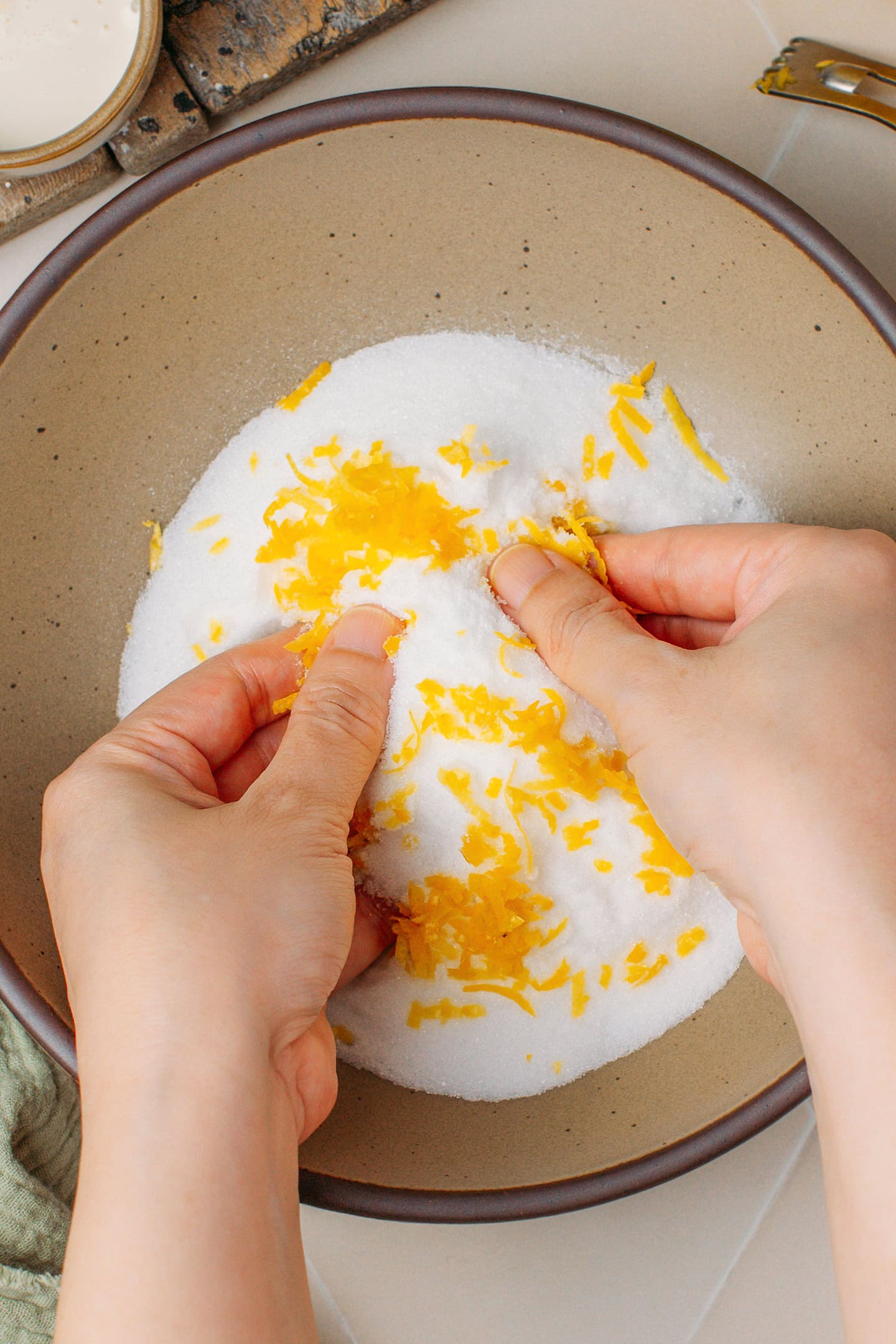 Rubbing lemon zest with sugar in a bowl.