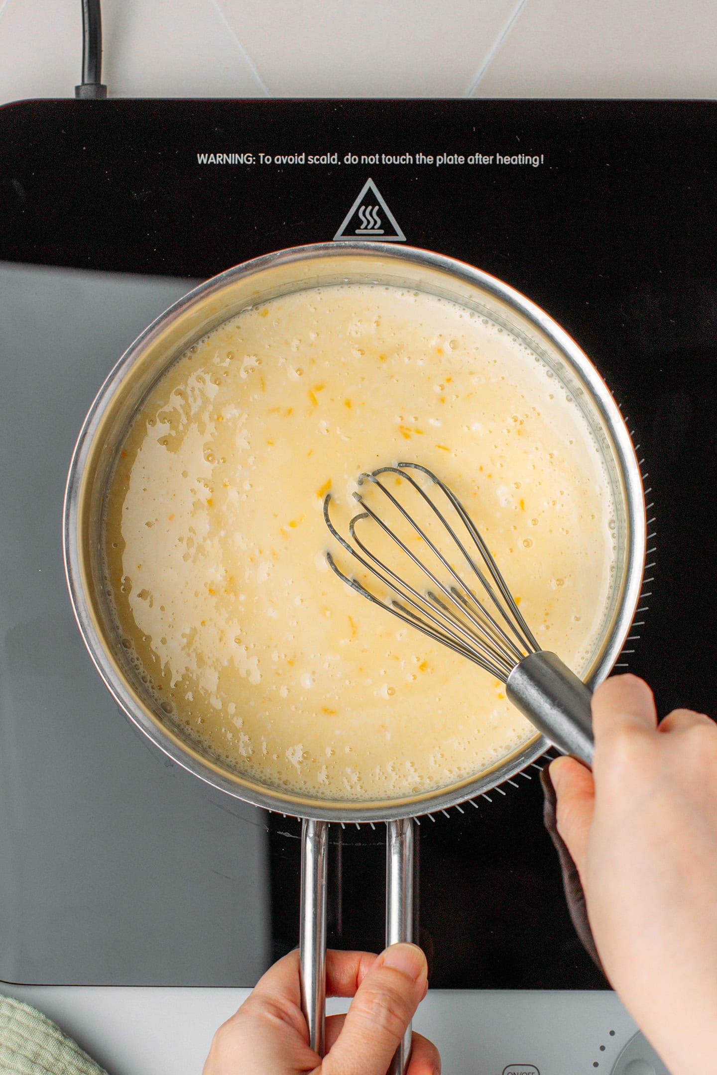 Whisking plant-based cream with cornstarch, lemon zest, and lemon juice.