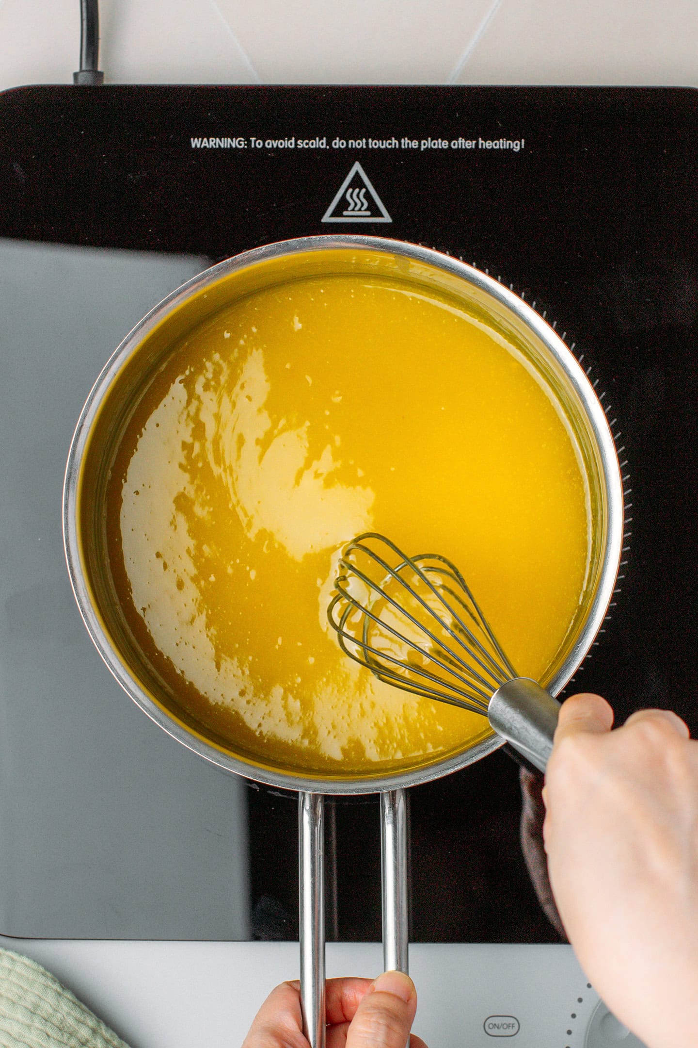 Whisking lemon curd in a saucepan.