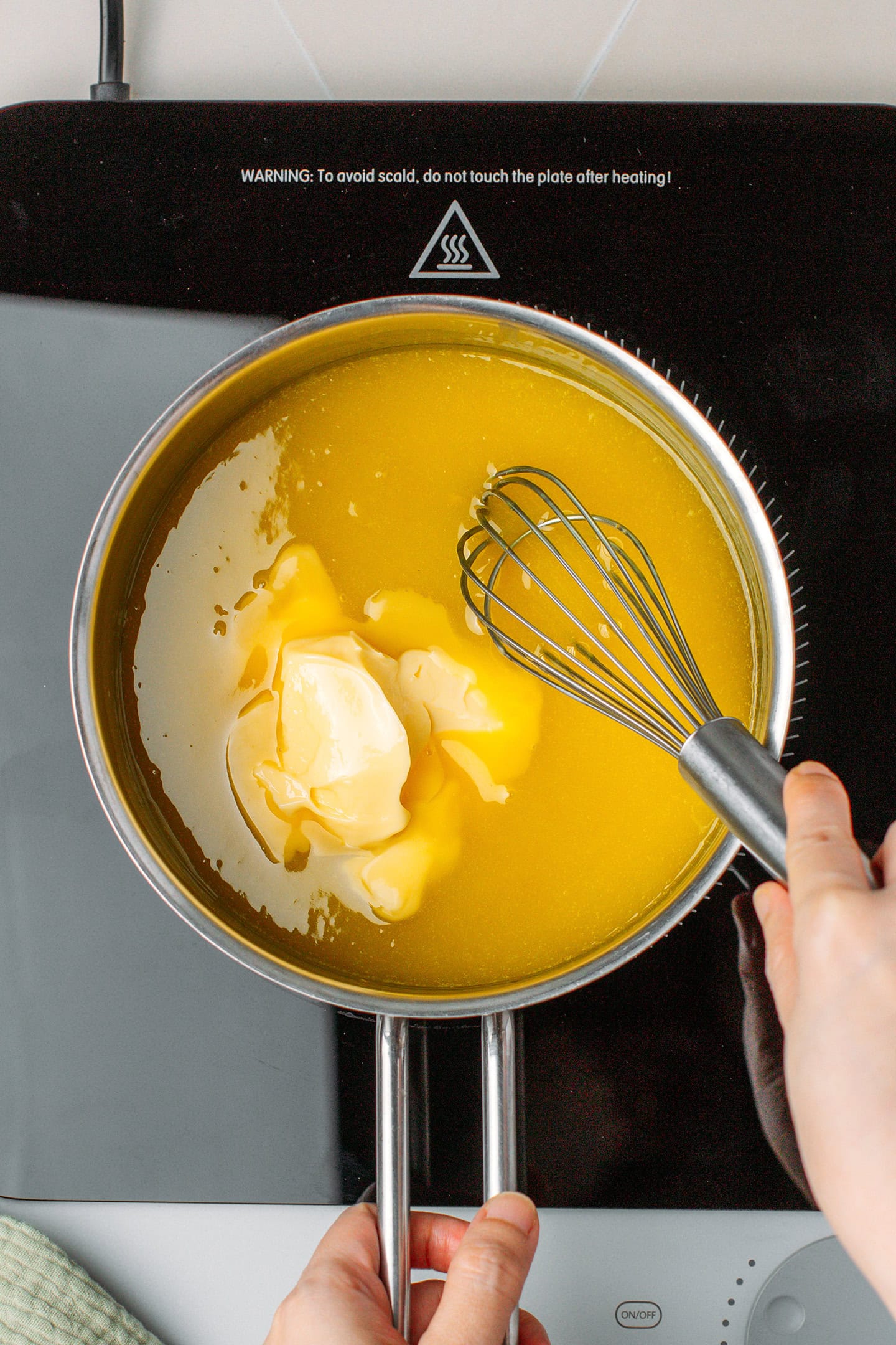 Whisking butter and lemon curd in a saucepan.