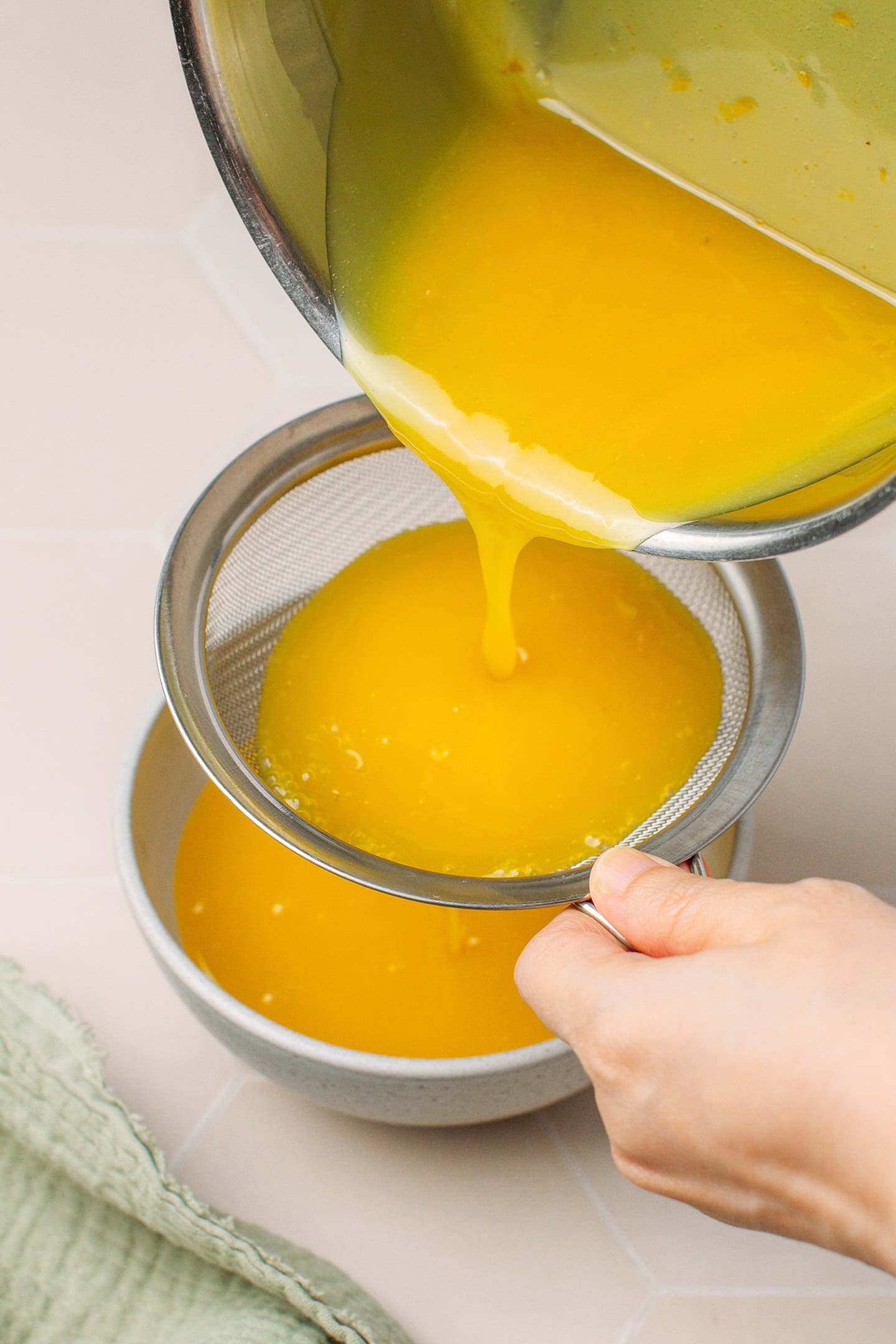 Straining lemon curd through a fine-mesh sieve.