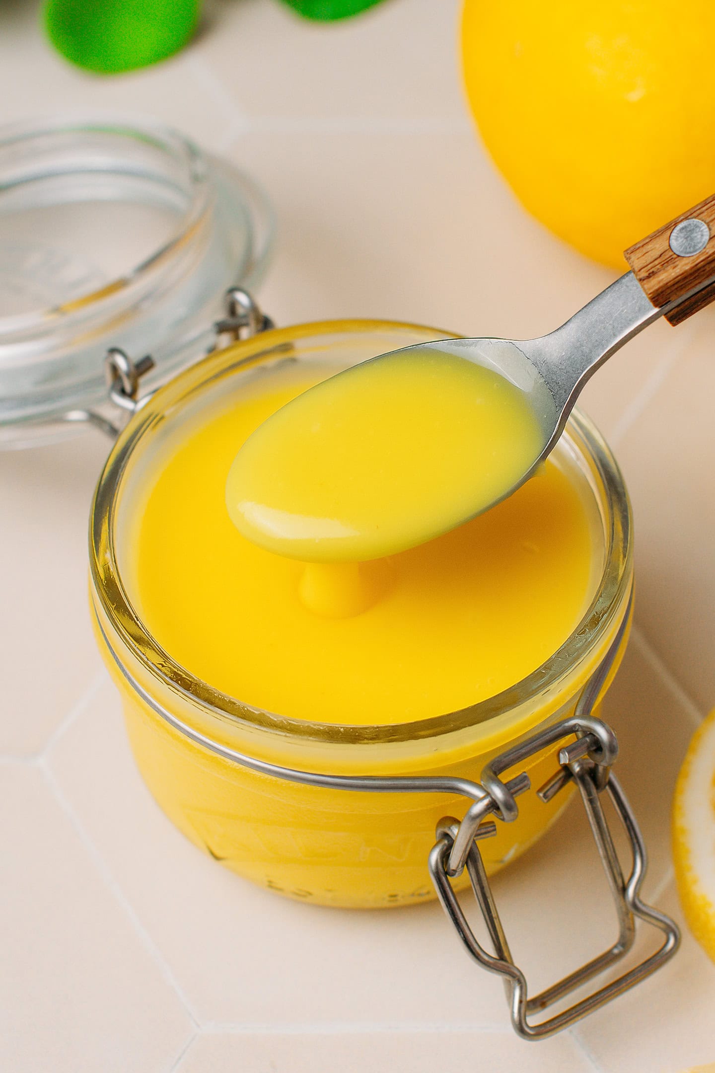 Spoonful of lemon curd over a glass jar.