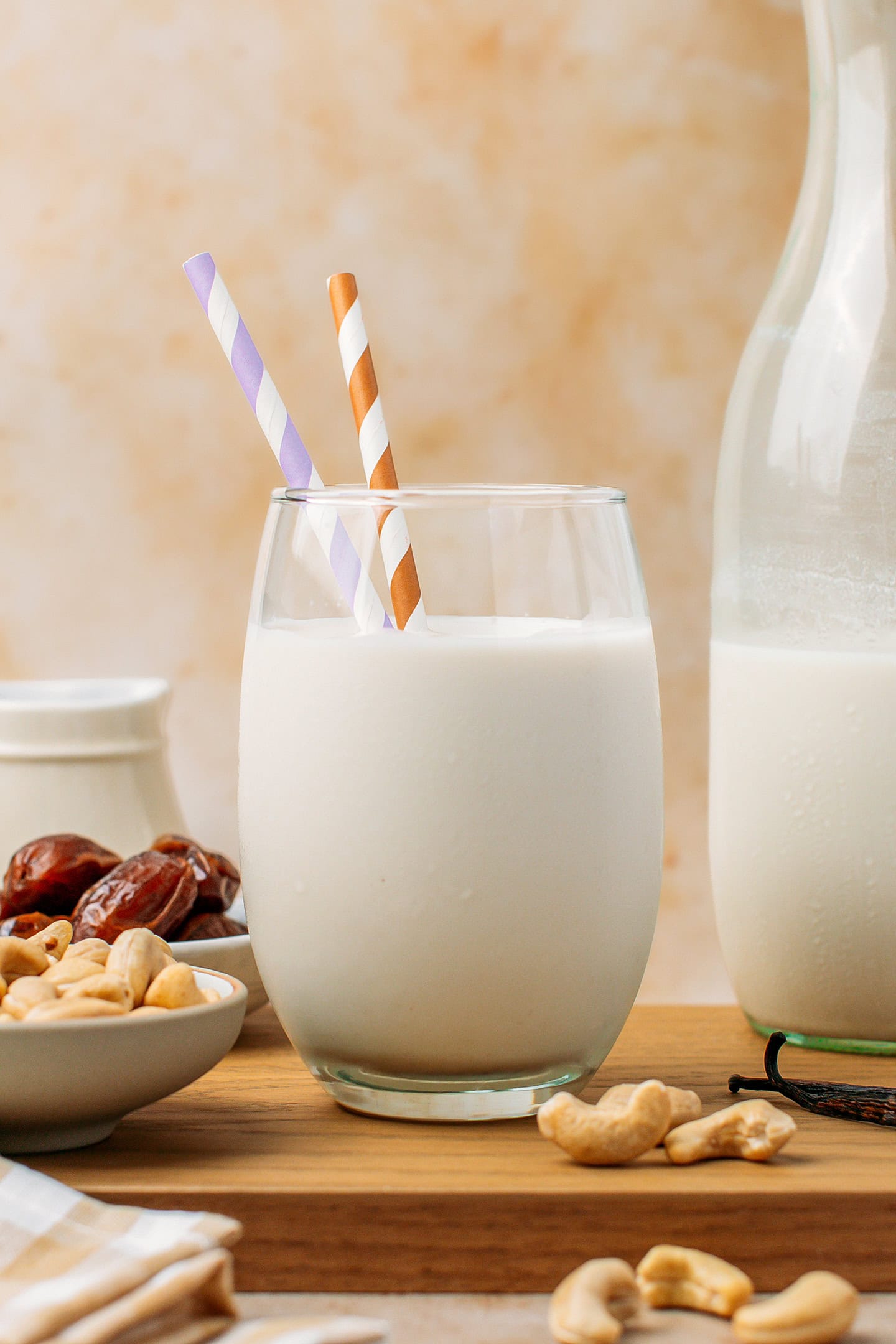 Glass of fresh cashew milk with two colorful straws.