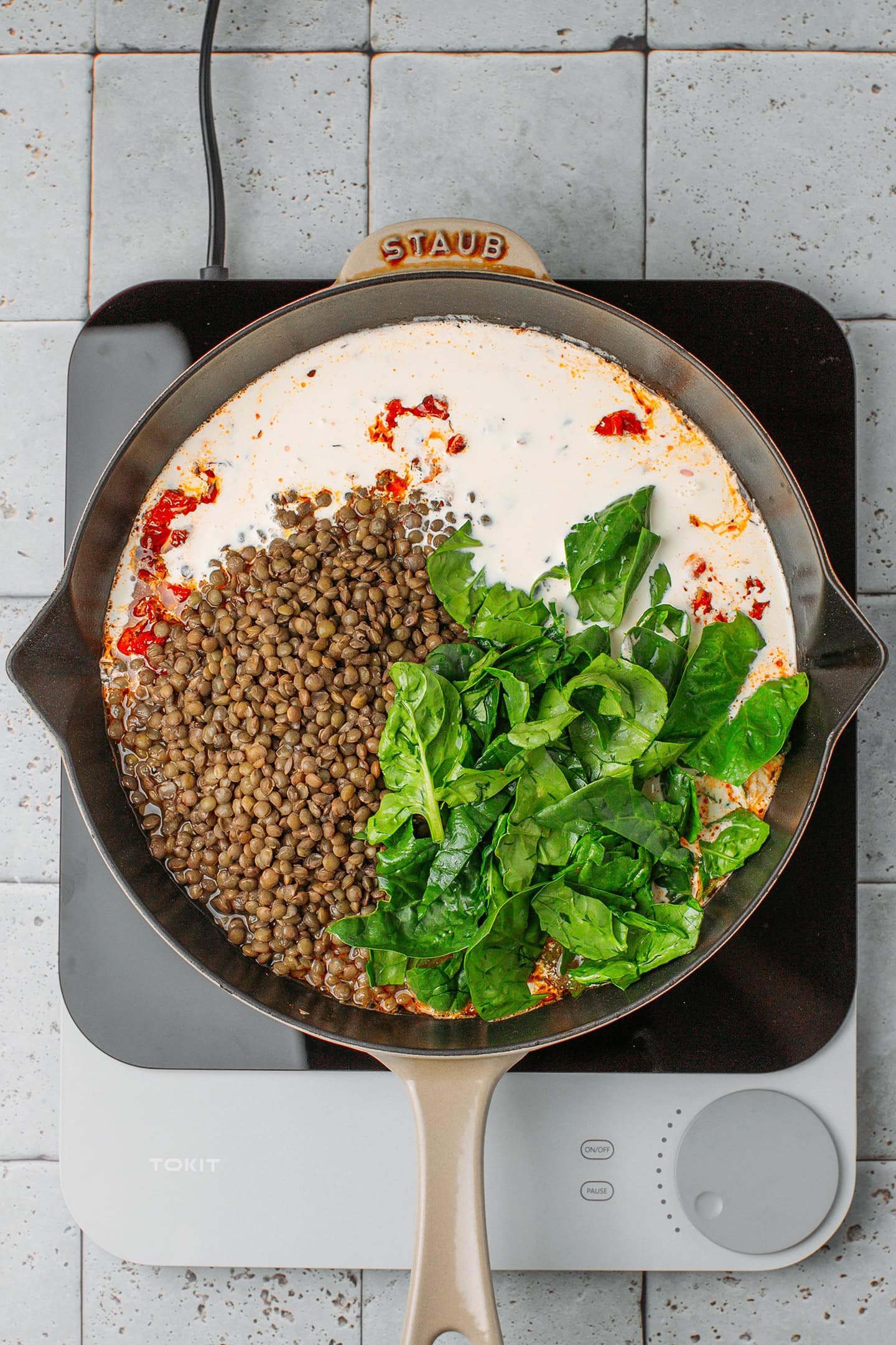 Vegan cream, green lentils, and spinach in a skillet.