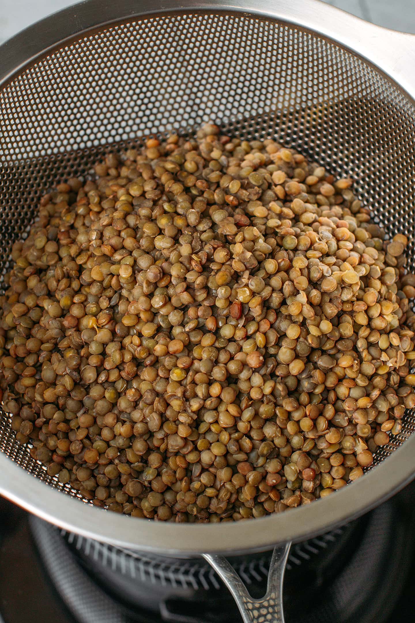 Cooked green lentils in a colander.