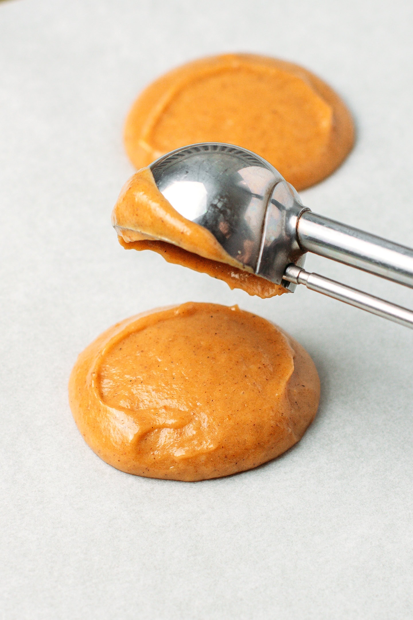 Dropping pumpkin batter rounds on a baking sheet.
