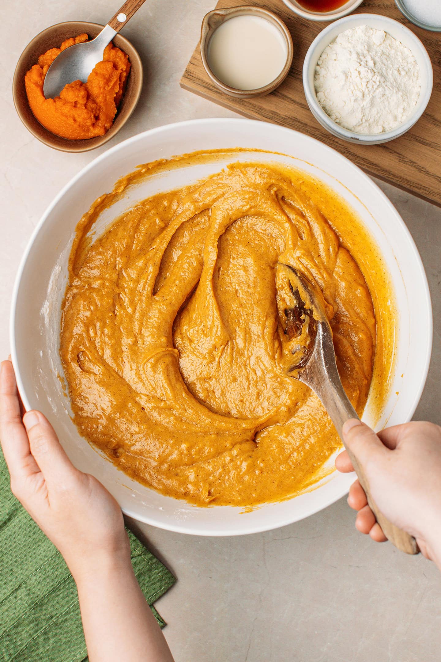 Mixing pumpkin muffin batter in a mixing bowl.