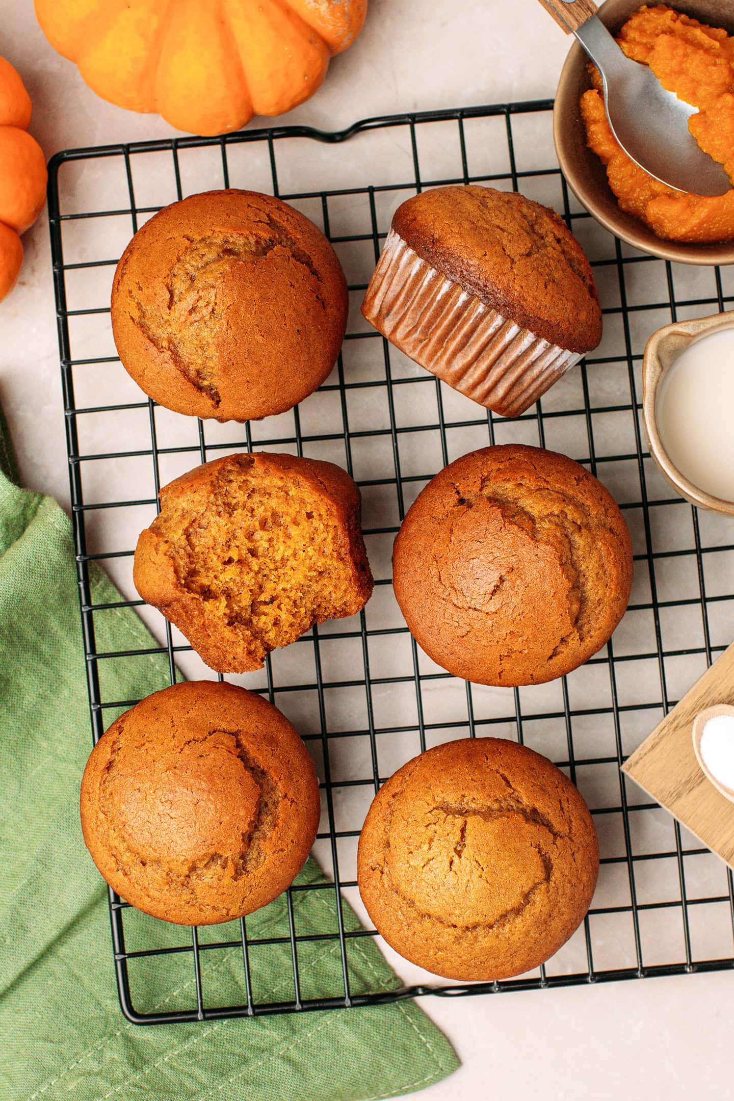 Six pumpkin muffins on a black cooling rack.
